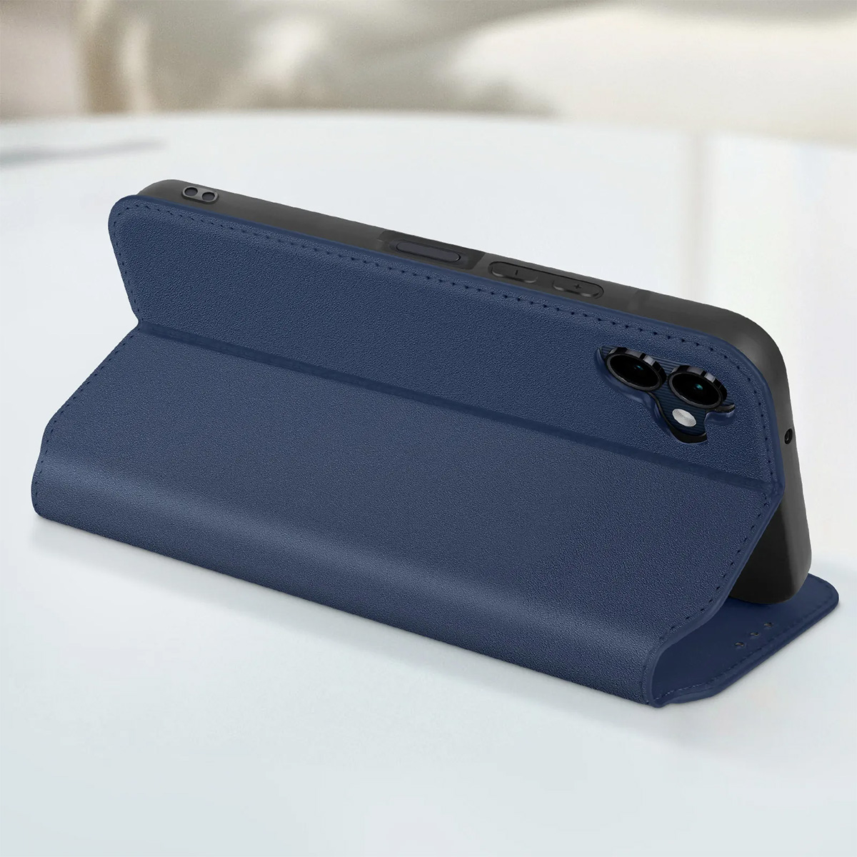 Una custodia blu per telefono è aperta, rivelando un telefono. La custodia è su una superficie bianca. Lo sfondo è sfocato.