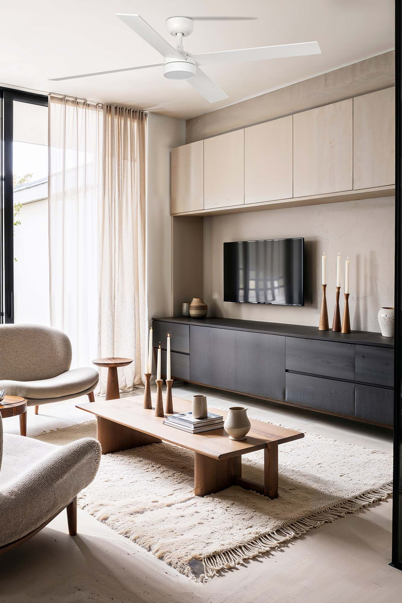 Wohnzimmer mit Deckenventilator, Sofa, Holztisch, Teppich, Fernseher und Kerzen auf einem dunklen Schrank.