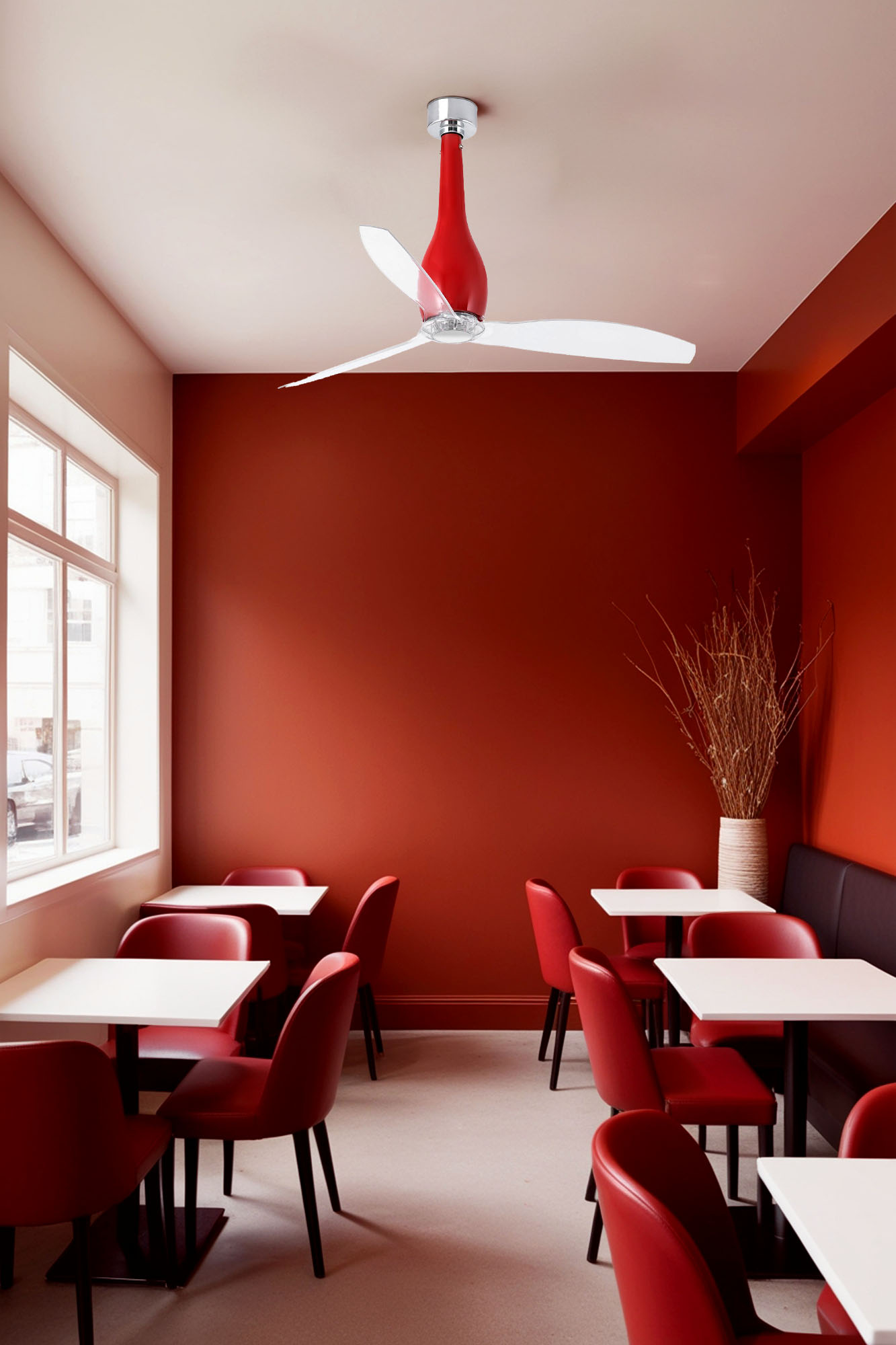 Ein Restaurantinterieur. Rote Wände und Stühle mit weißen Tischen. Ein roter und silberner Deckenventilator. Ein Fenster links.