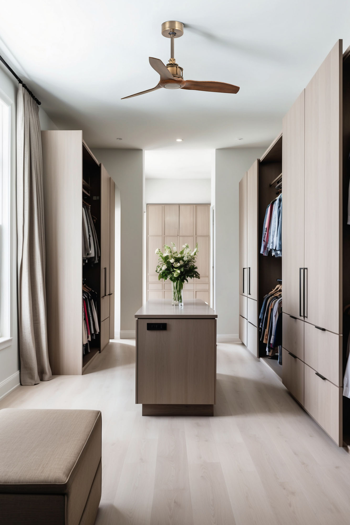 Begehbarer Kleiderschrank mit hellen Holzschränken, Kleidung und einer zentralen Insel mit Blumen. Ein Deckenventilator hängt über dem Raum.