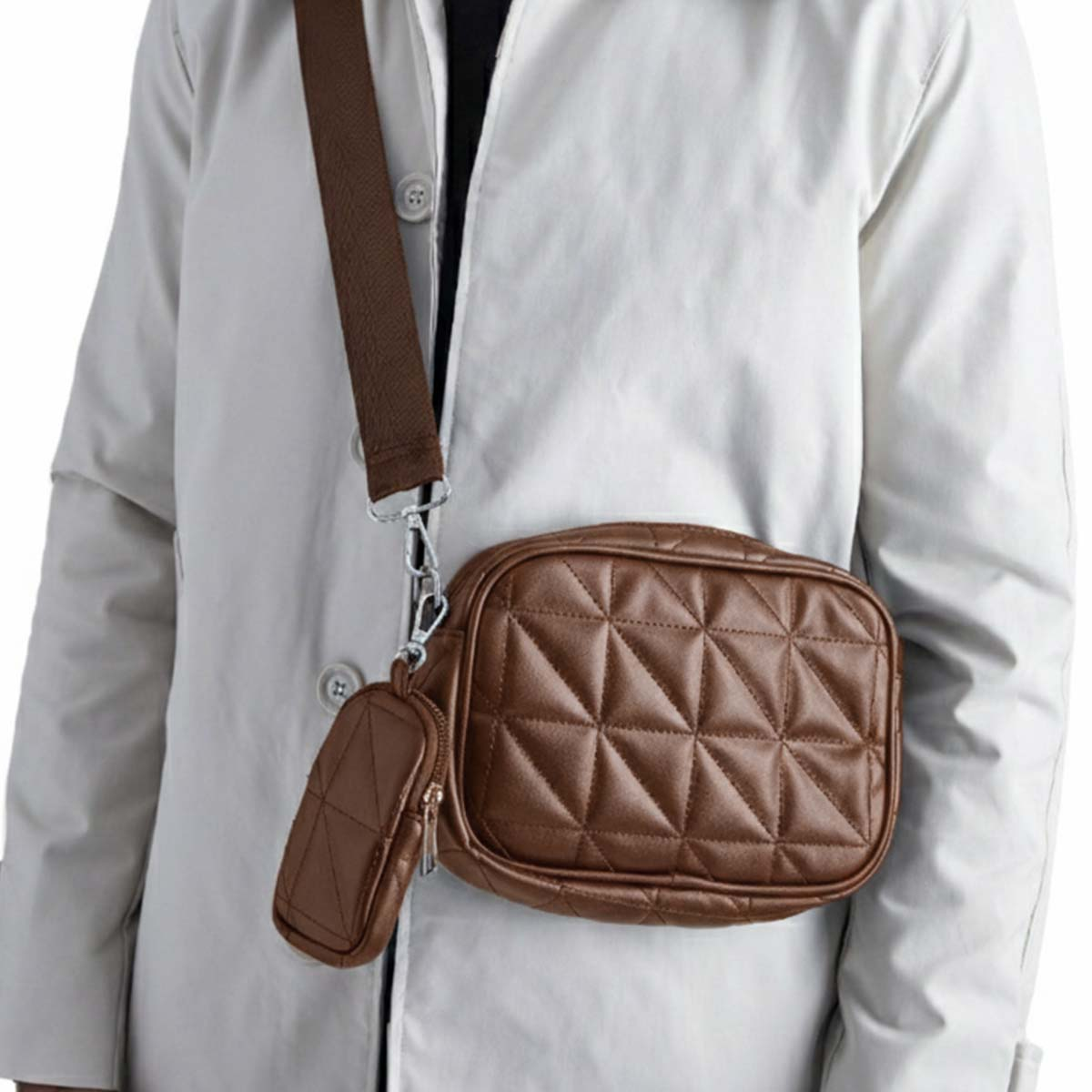 Una persona indossa un cappotto grigio chiaro con una borsa a tracolla trapuntata marrone e una piccola pochette.