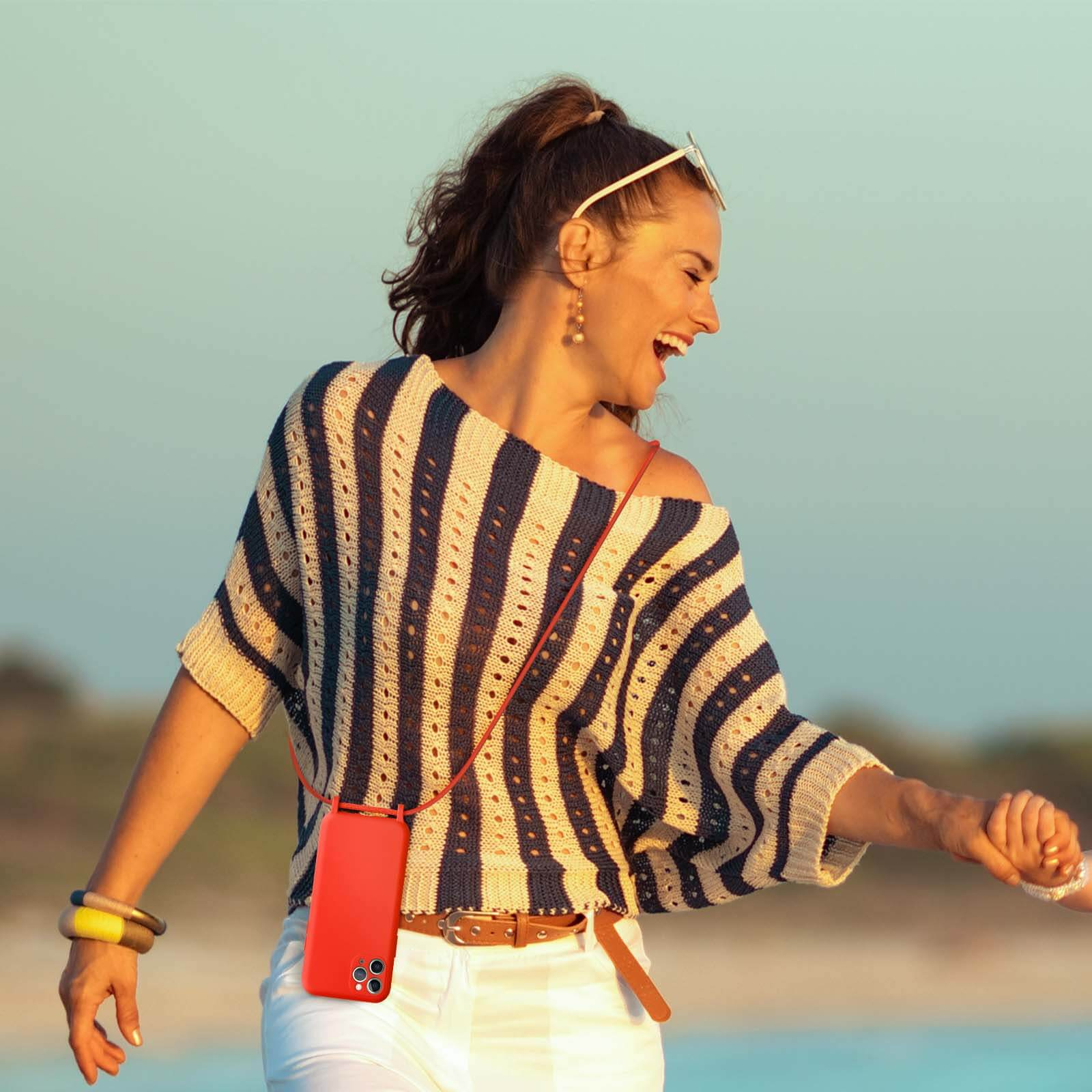 Femme riant, haut rayé, tenant un téléphone, pantalon blanc, lunettes de soleil, bracelets. Fond bleu clair.