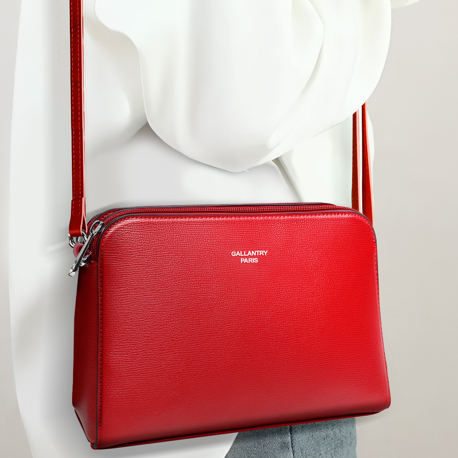 Un bolso bandolera de cuero rojo con la marca Gallantry Paris, colgado de un maniquí blanco.