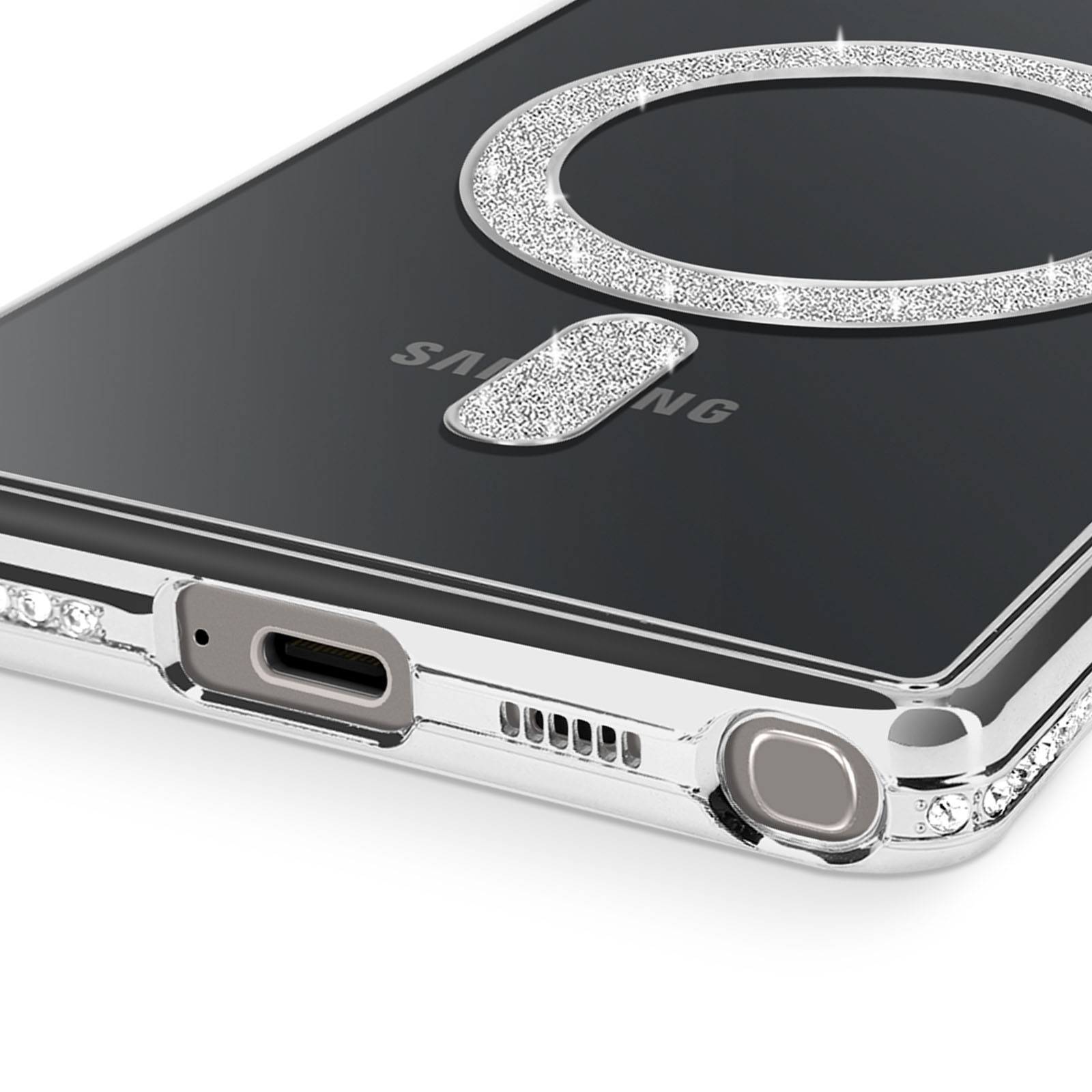 Primo piano di una custodia per telefono con un design ad anello di diamanti su una superficie nera. Bordi argentati e strass visibili.