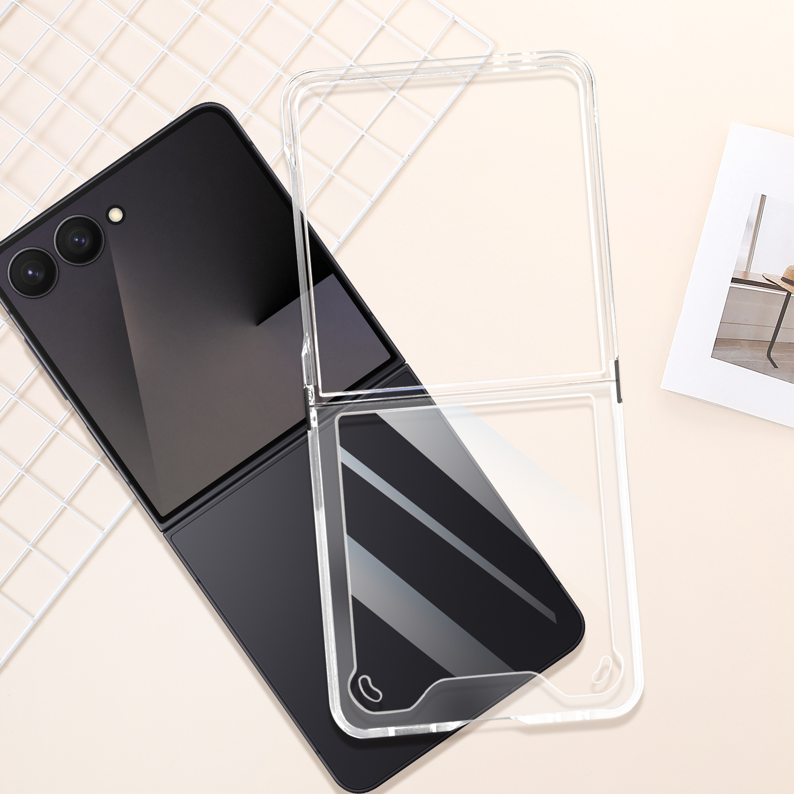 Téléphone pliable noir avec étui transparent, sur surface beige clair. Grille blanche et photo en arrière-plan.