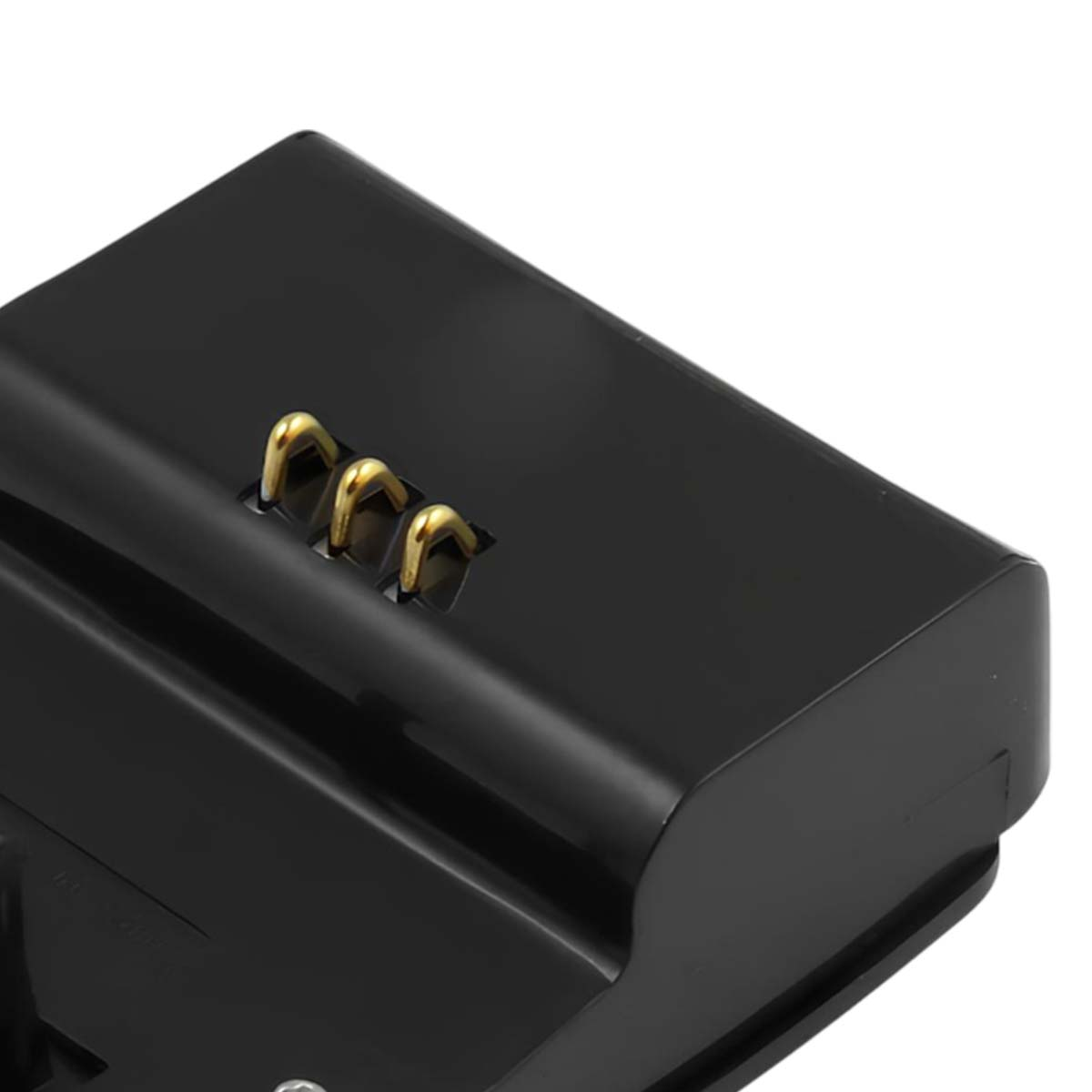 Nahaufnahme eines schwarzen Batterieladegeräts mit drei goldfarbenen Metallkontakten auf der Oberseite. Das Ladegerät hat eine glänzende Oberfläche.