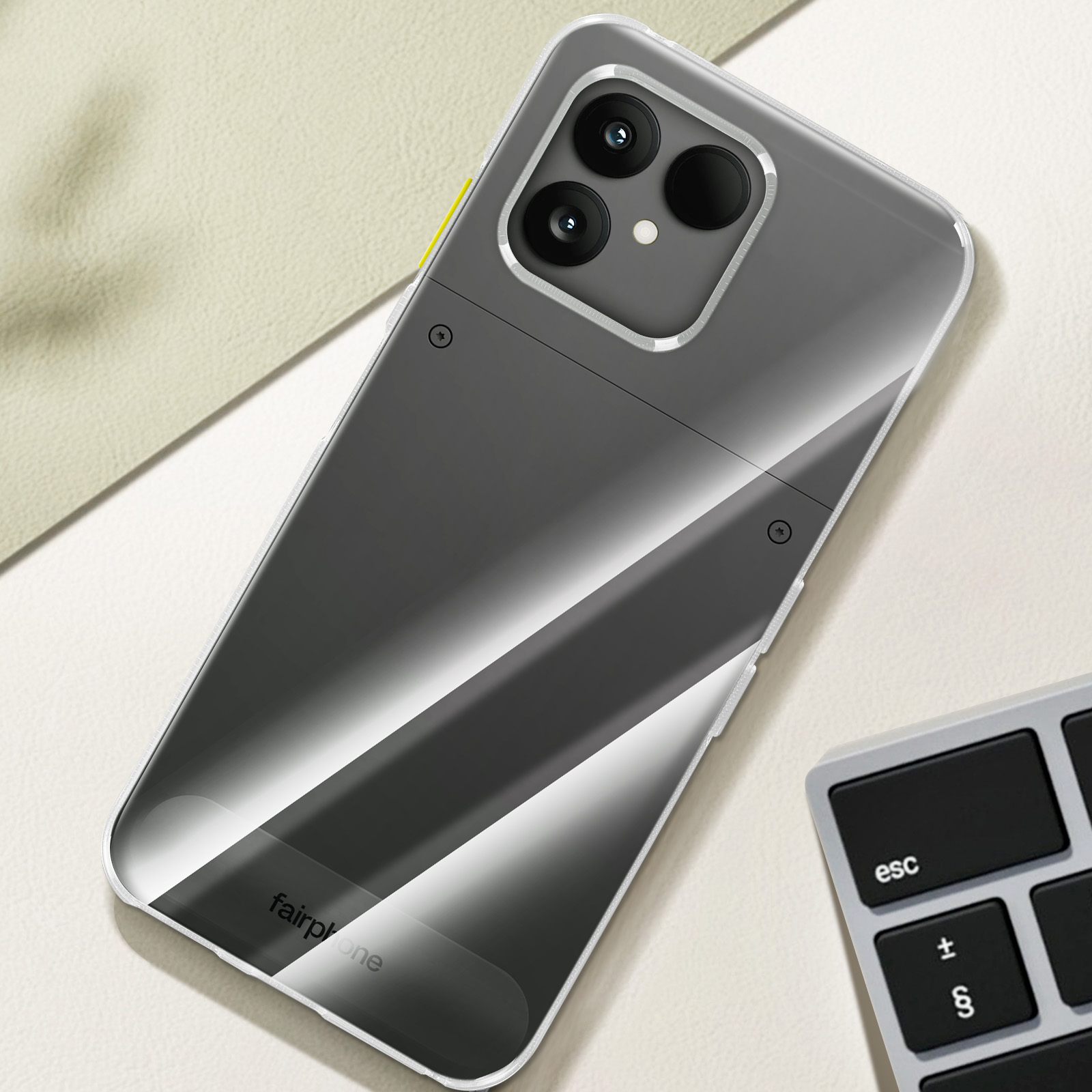 Telefoonhoesje op een beige oppervlak met een toetsenbord in de hoek. De hoes is zwart en grijs.