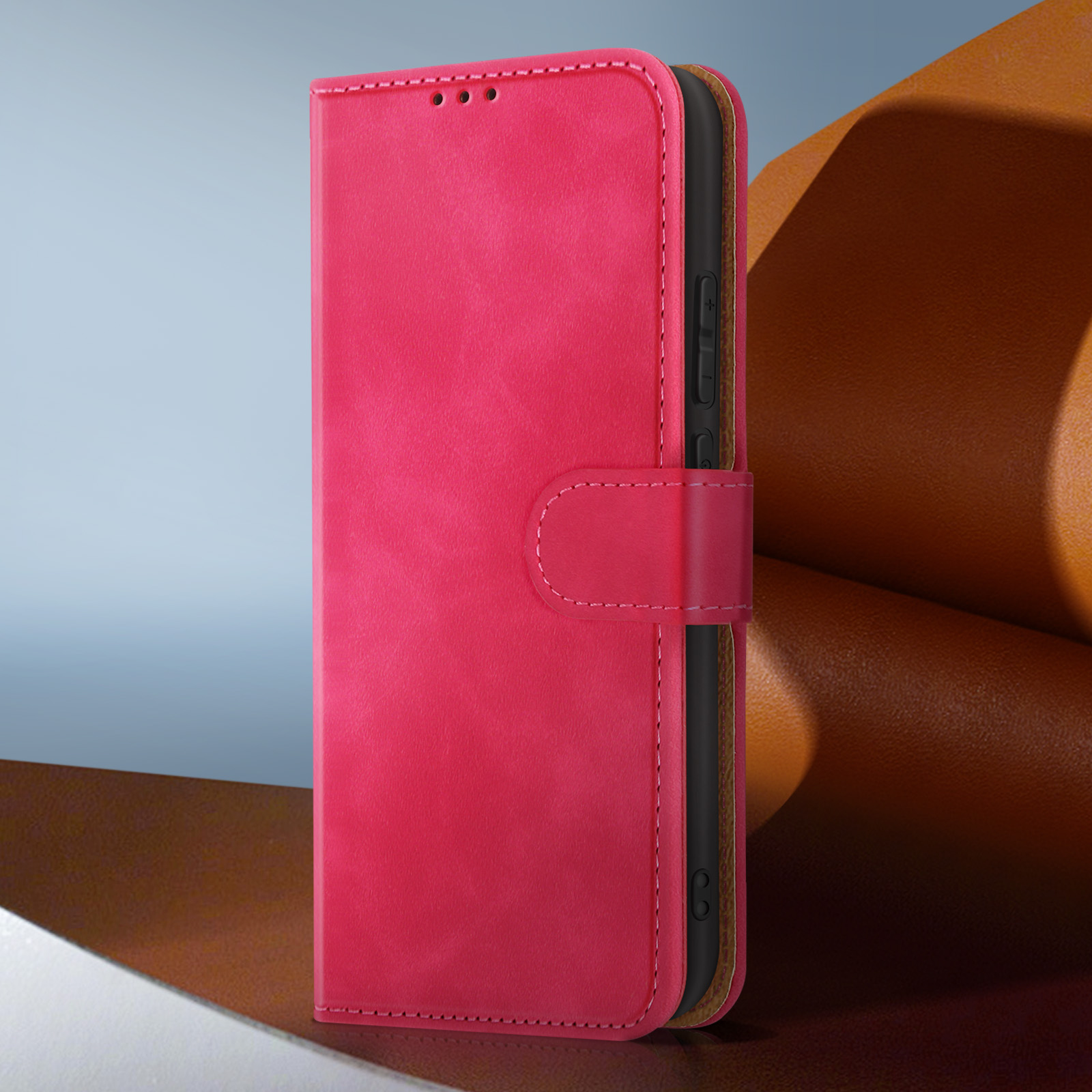 Una custodia rosa per telefono con chiusura magnetica, aperta per rivelare un telefono nero all'interno. Lo sfondo è marrone e grigio.