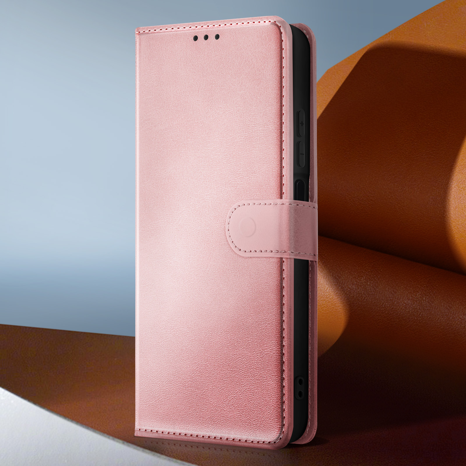 Una custodia per telefono in pelle rosa è in posizione verticale, chiusa con un cinturino. Lo sfondo presenta una sfumatura blu e marrone.