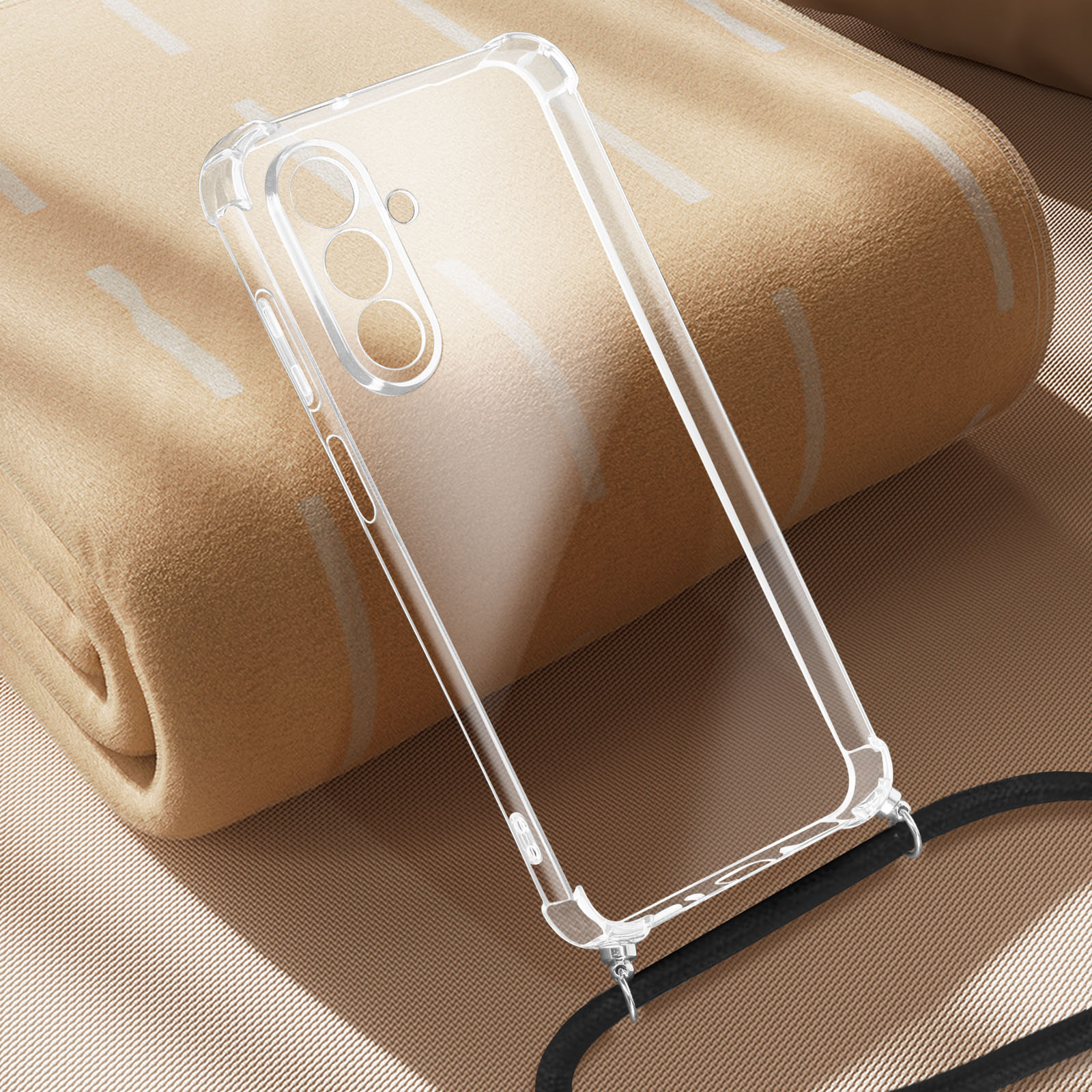 Una custodia trasparente con cinturino nero è su una coperta beige. La custodia ha tre fori per la fotocamera.