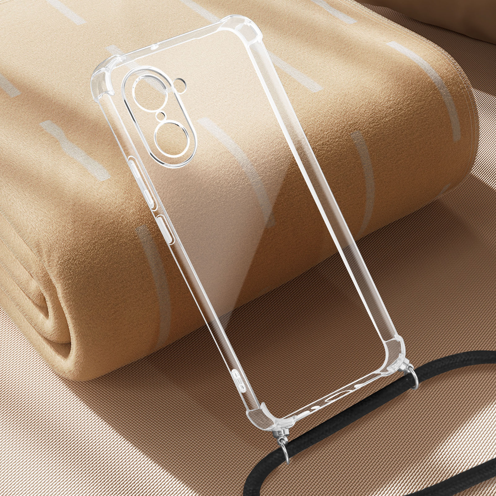 Une coque de téléphone transparente est sur une couverture beige. La coque a un cordon noir. La couverture a des lignes blanches.