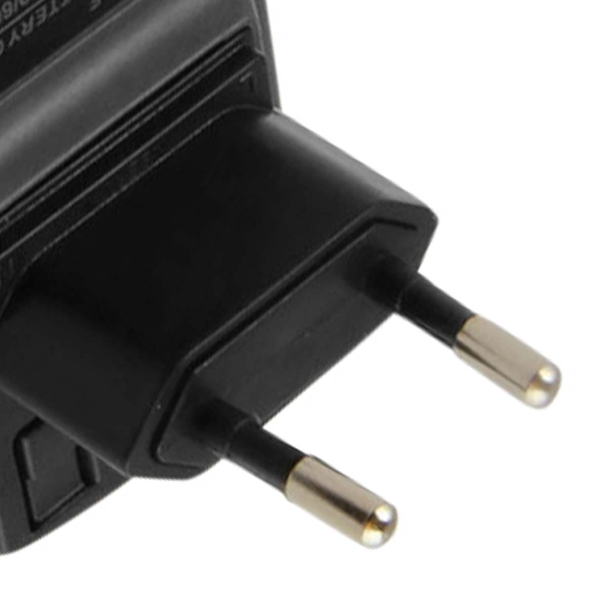 Primer plano de un adaptador de corriente negro con dos clavijas plateadas. El adaptador está en ángulo, mostrando parte del cuerpo.