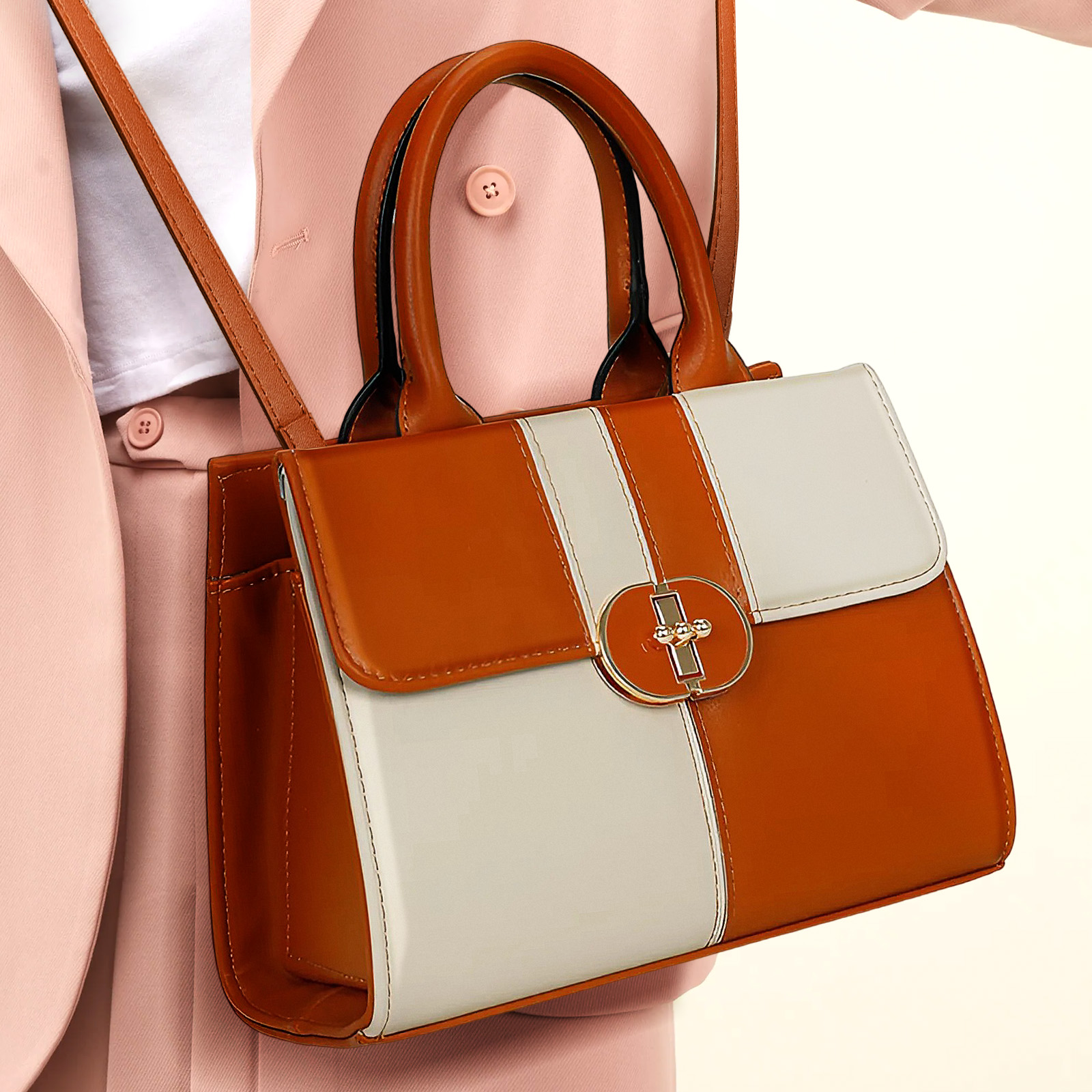 Un bolso marrón y blanco de dos tonos, con un cierre dorado, lo sostiene una persona con un traje rosa.