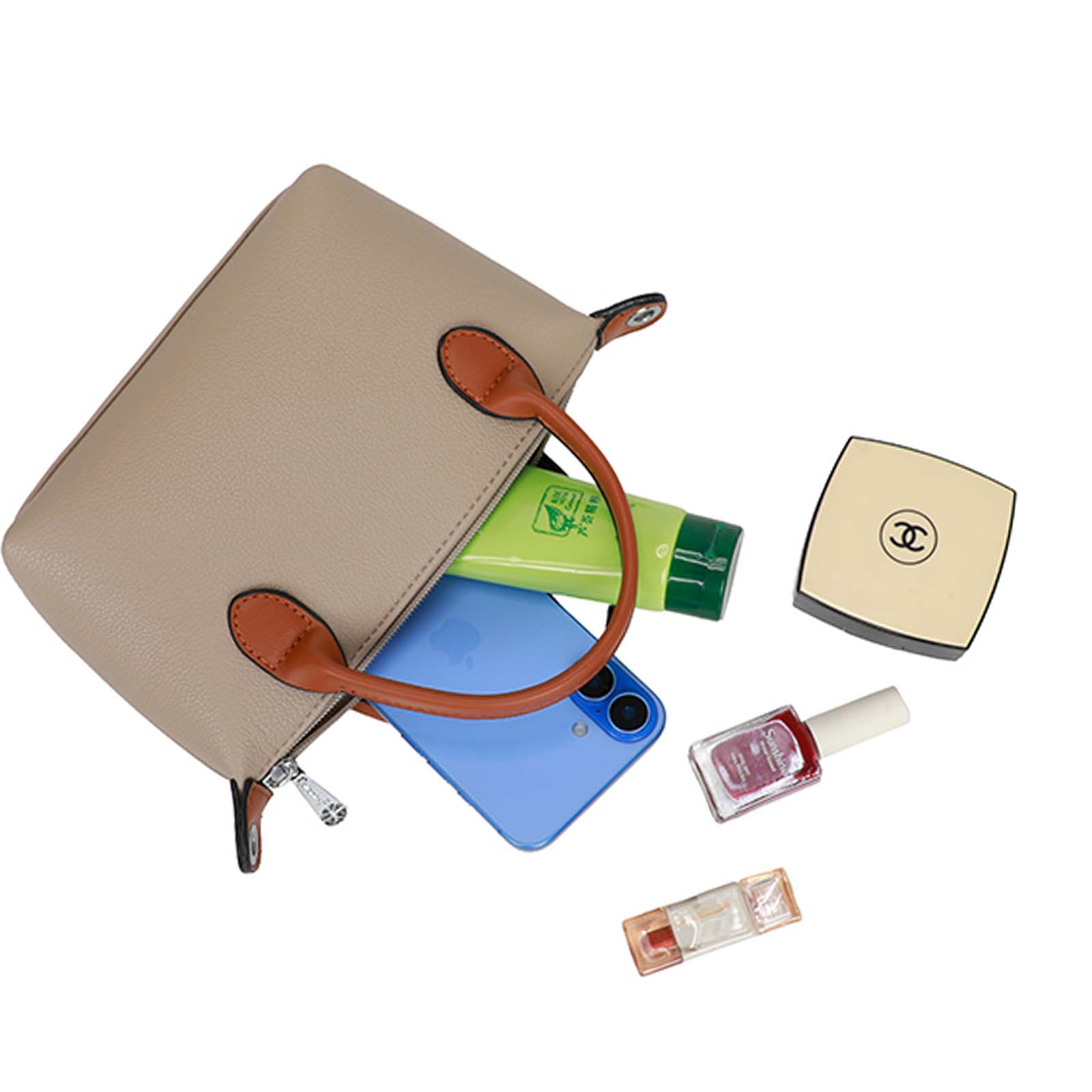 Un bolso beige con asas marrones, abierto para revelar un teléfono, un tubo verde, una polvera, esmalte de uñas y un brillo labial.