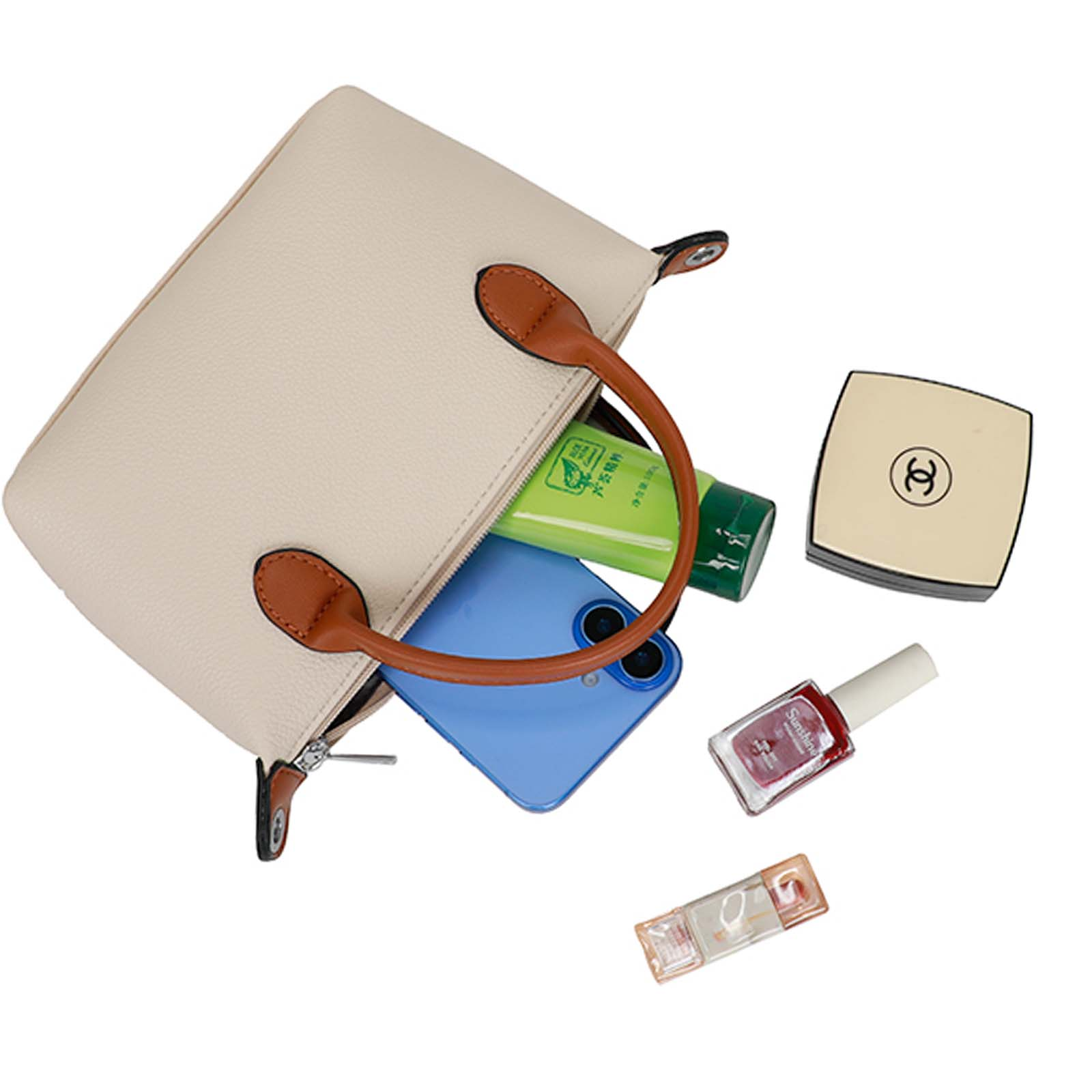 Un bolso crema con asas marrones, abierto con un teléfono azul, maquillaje y un tubo verde.