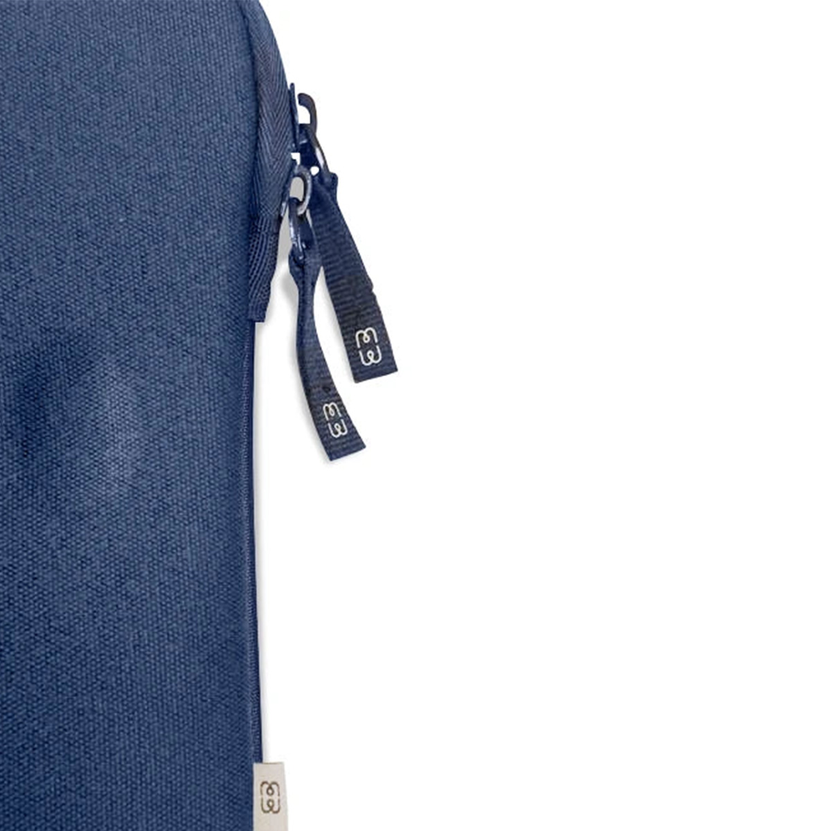 Primo piano di una borsa blu. Visibili una cerniera, due etichette in tessuto con testo bianco e un'etichetta bianca.