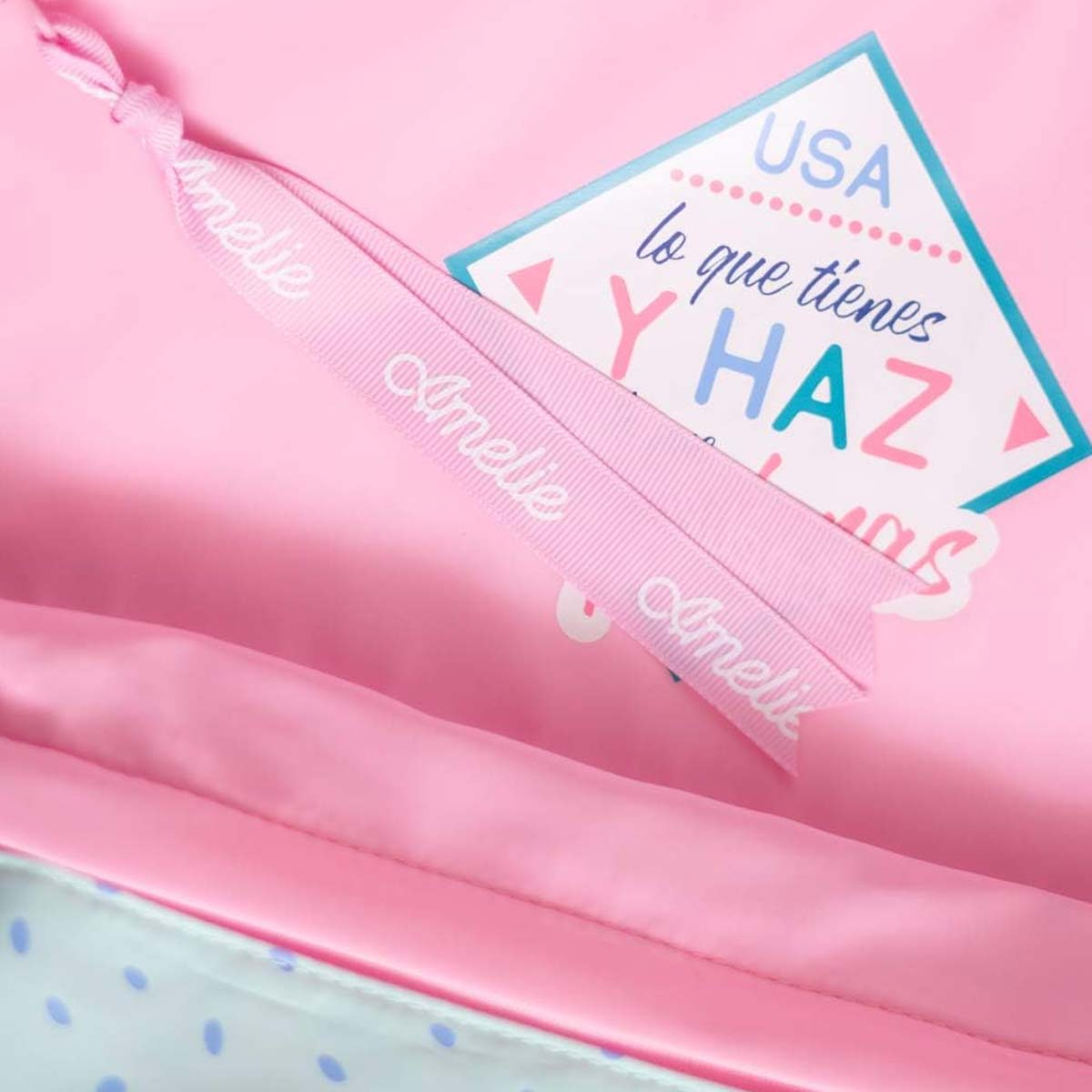 Borsa rosa con un nastro con scritto 'Amelie'. Un'etichetta dice 'USA' e 'lo que tienes Y HAZ'.