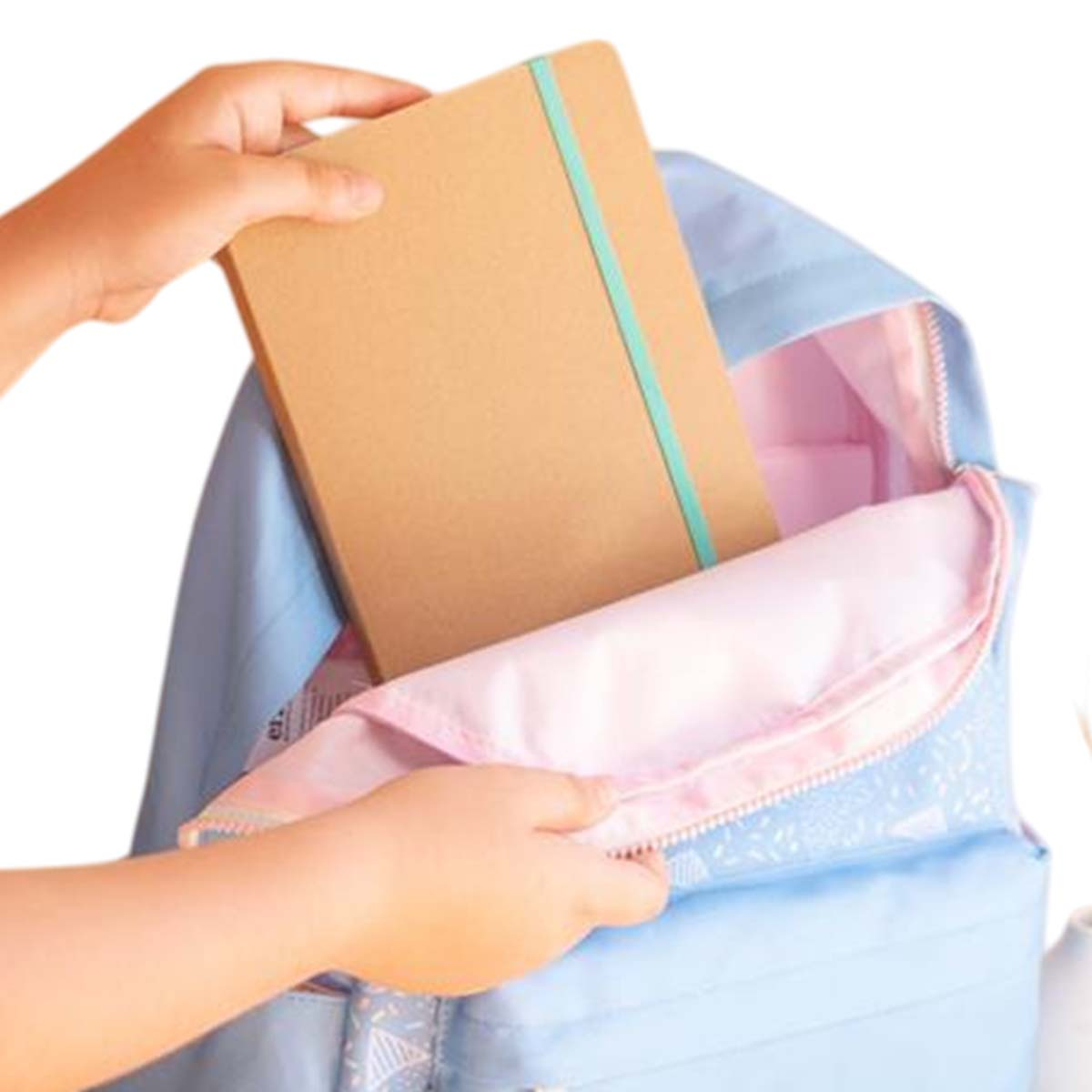 Una persona mette un quaderno marrone con una fascia verde in uno zaino azzurro con interno rosa.