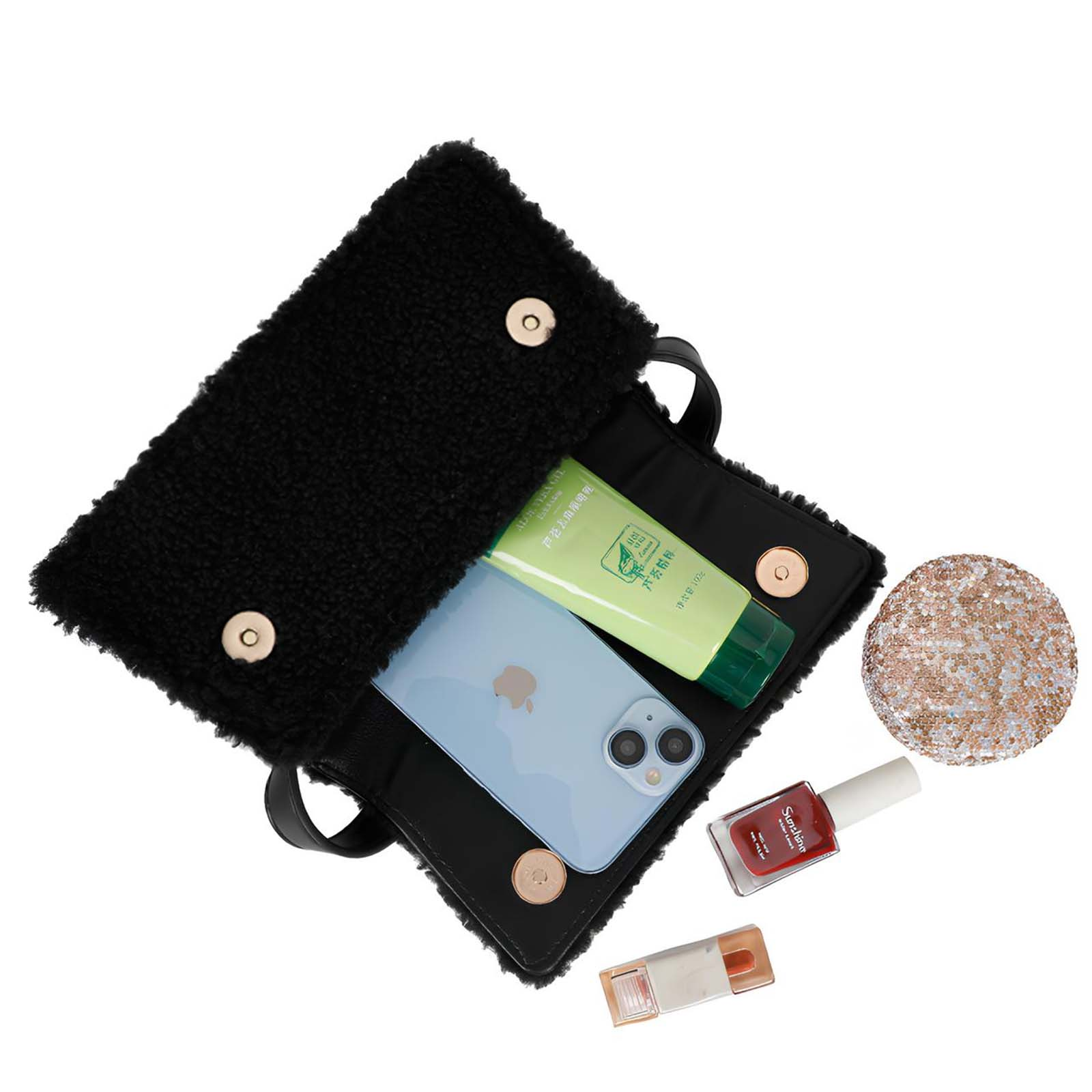 Bolso negro abierto con teléfono, crema, esmalte de uñas y un compacto con lentejuelas. Elementos sobre fondo blanco.