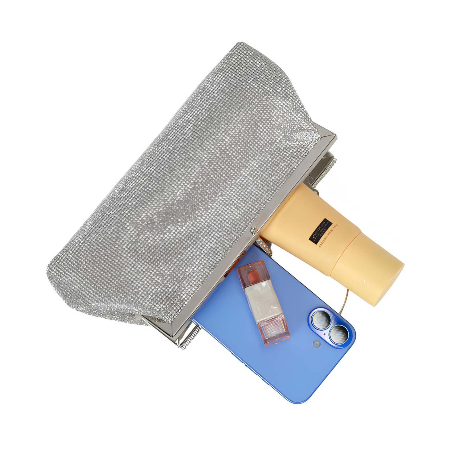 Una pochette argentata, aperta, rivela un telefono, un tubetto di crema e un rossetto. Tutto su sfondo bianco.
