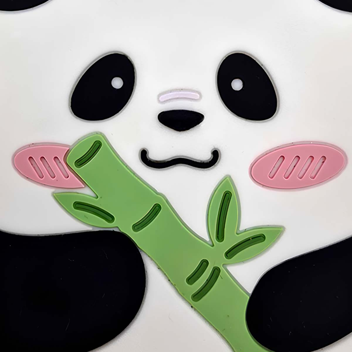 Primer plano de la cara de un panda con ojos negros, mejillas rosas y bambú verde. El panda es blanco y negro con un diseño de dibujos animados.