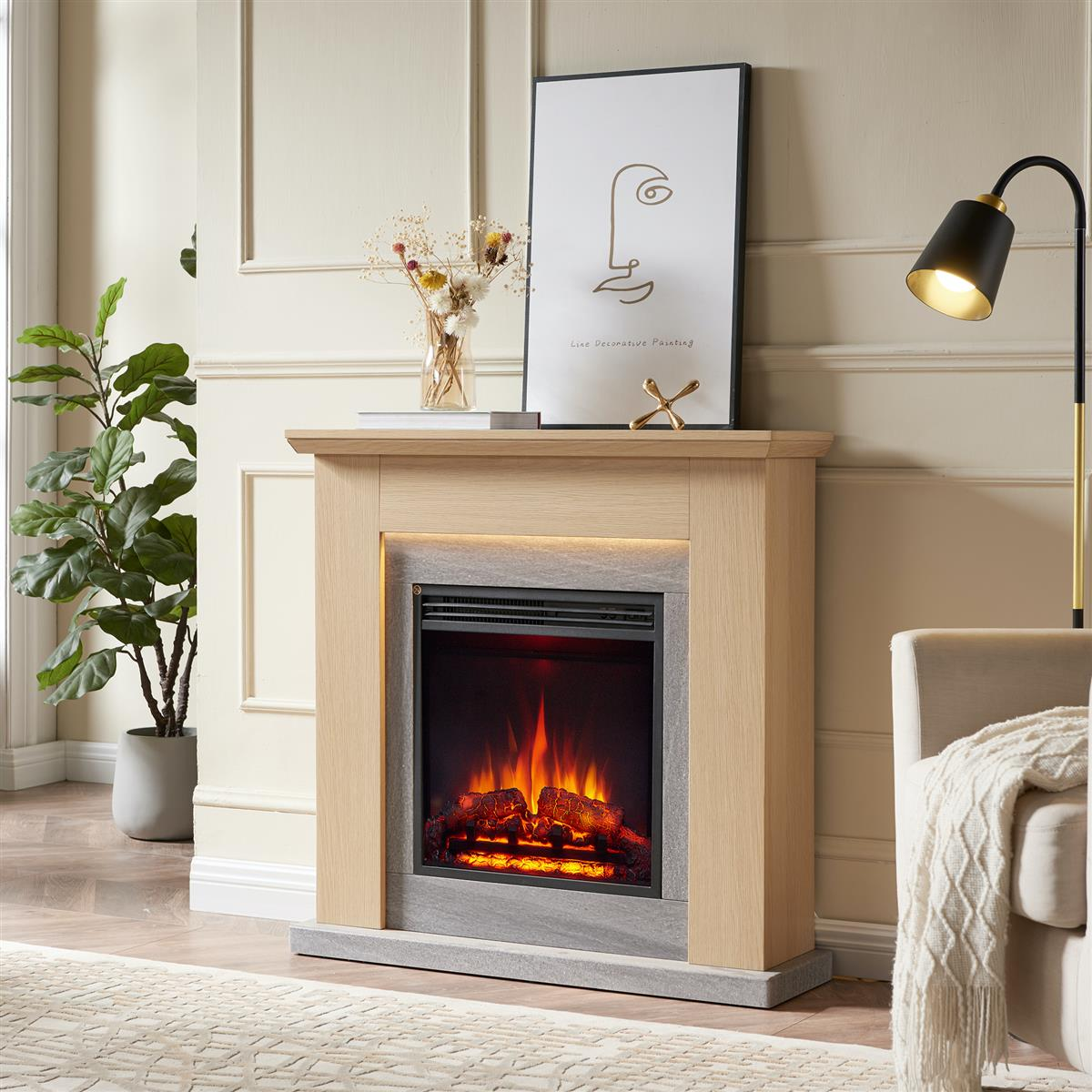 Kamin mit Flammen, Kunstwerk, Blumen und Stehlampe. Eine Pflanze steht neben dem Kamin. Im Hintergrund ein Stuhl.