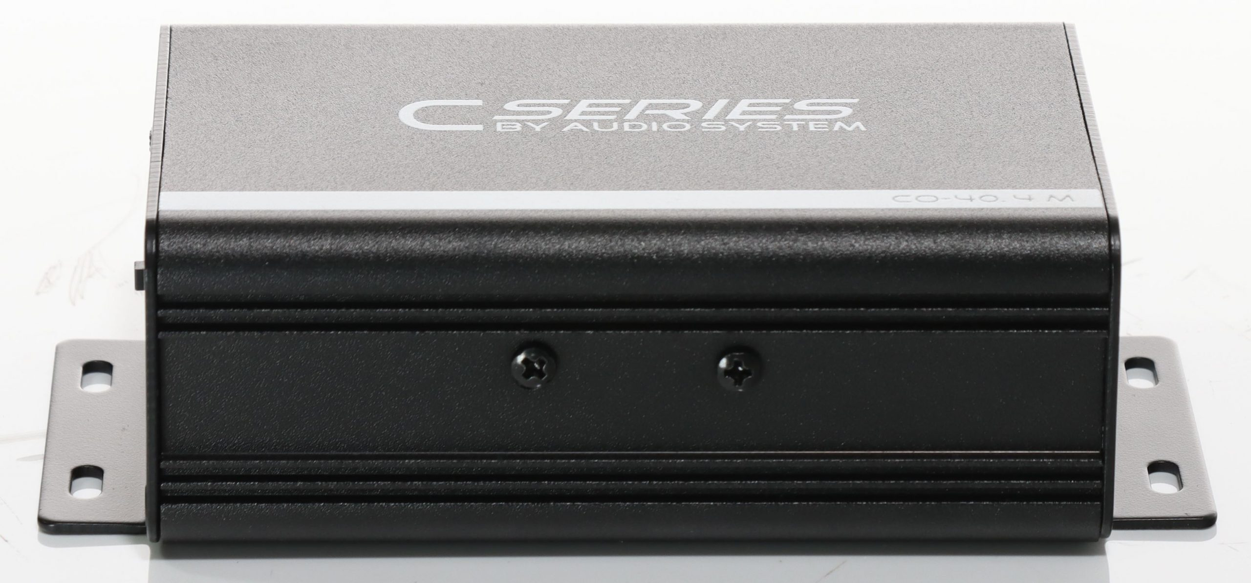 Ein schwarz-graues elektronisches Gerät mit der Aufschrift 'C SERIES BY AUDIO SYSTEM'. Es hat Halterungen und Schrauben.