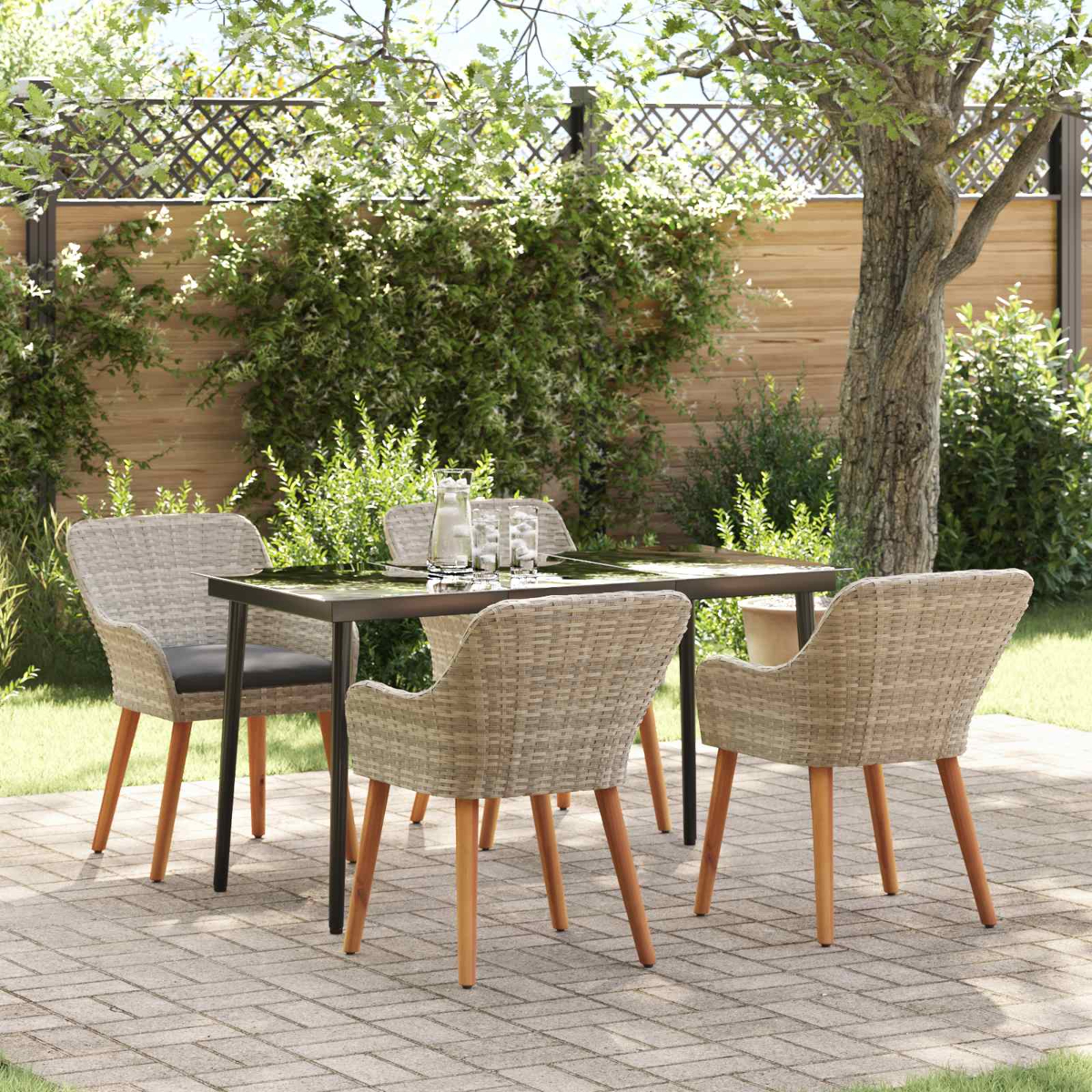 Terrassengarnitur: Tisch, vier Stühle. Grünes Laub und Baum im Hintergrund. Backstein-Patio. Gläser auf dem Tisch.