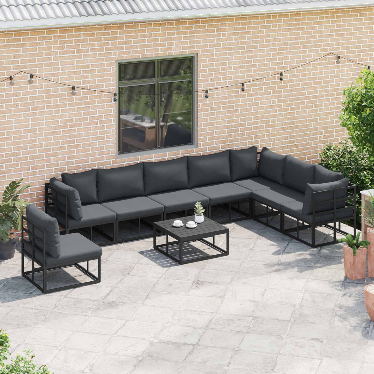 Set di sedute da esterno con cuscini grigio scuro. Include un divano componibile, due sedie e un tavolino.