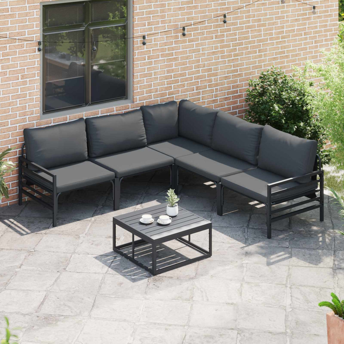 Garten-Terrassenset mit dunkelgrauen Kissen. Enthält ein Ecksofa, einen quadratischen Couchtisch und kleine Pflanzen.