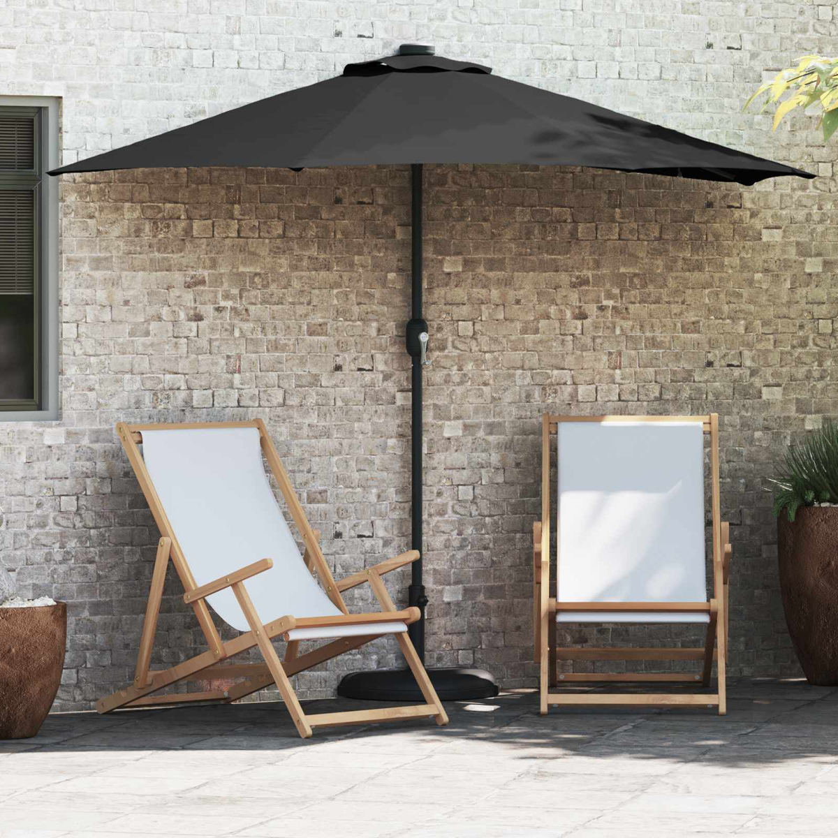 Una scena del patio con un ombrello nero, due sedie in tela bianca e un muro di mattoni sullo sfondo.
