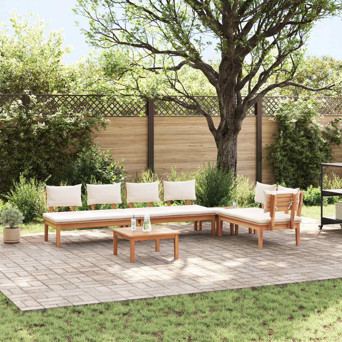 Garten-Sitzgruppe auf einer Terrasse. Enthält einen Tisch, zwei Bänke und zwei Stühle. Umgeben von Grün und einem Holzzaun.