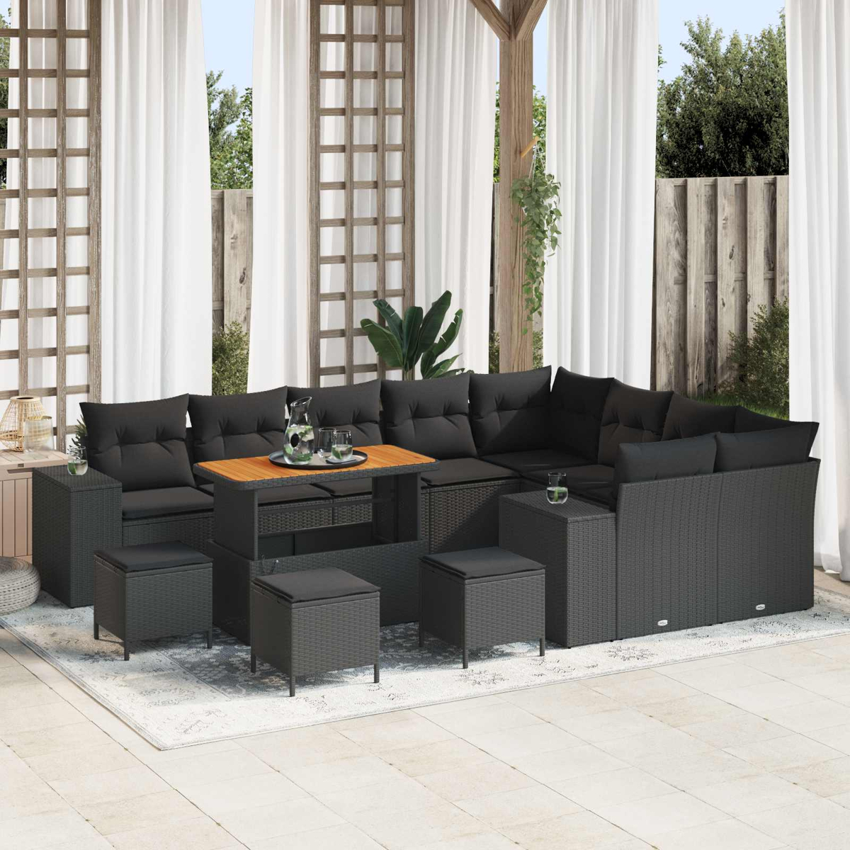 Terrassenset mit schwarzen Kissen und Tisch. Weiße Vorhänge und Holzgitter im Hintergrund. Topfpflanzen und Teppich.