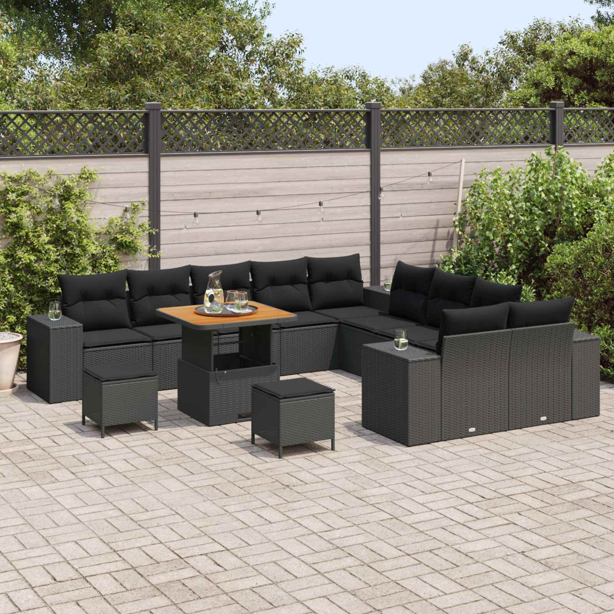 Garten-Set mit schwarzen Kissen, Tisch mit Holzplatte und grauem Zaun im Hintergrund.
