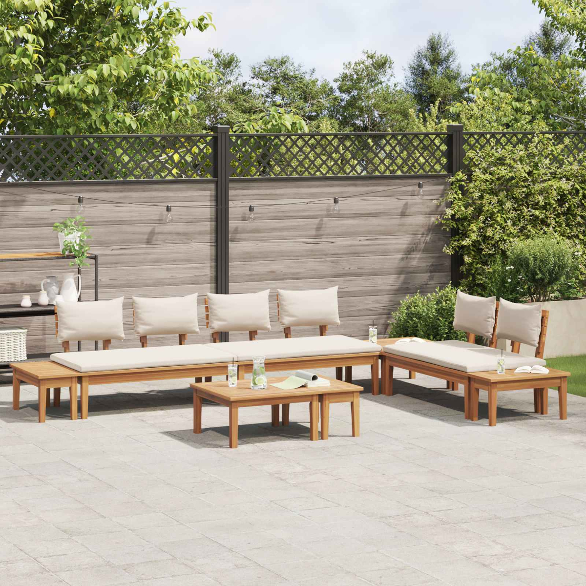 Garten-Sitzgruppe auf der Terrasse. Beinhaltet Bänke, Stühle und Tisch. Beige Kissen. Holzmöbel. Grüne Pflanzen und Holzzaun im Hintergrund.