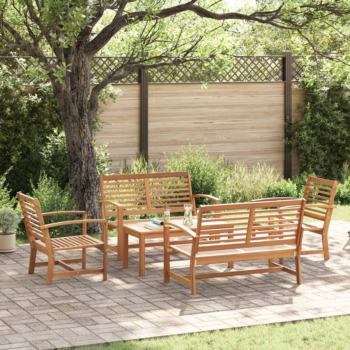 Holz-Terrassenmöbel-Set mit Tisch, zwei Stühlen und einer Bank. Auf einer Ziegelterrasse, umgeben von Bäumen und Grün. 
