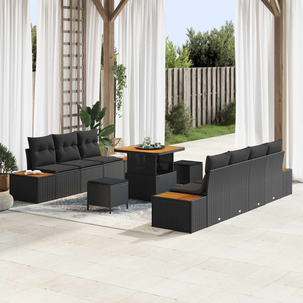 Garten-Terrassenset mit schwarzem Korbmöbel, Holztisch und weißen Vorhängen. Garten mit Holzzaun und Grün.