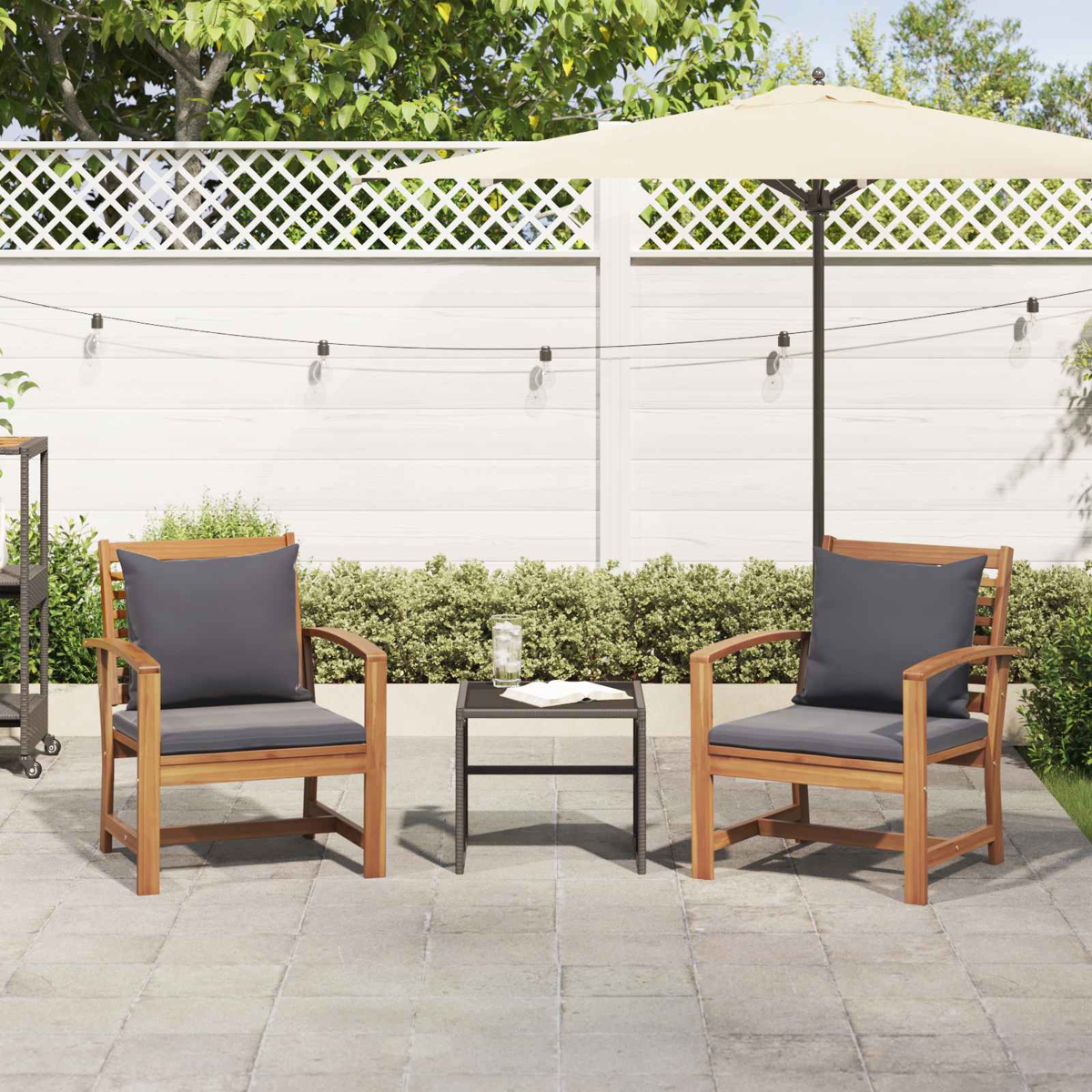 Patio-Szene mit zwei Holzstühlen mit grauen Kissen, kleinem Tisch und einem beigen Sonnenschirm. Weißer Zaun im Hintergrund.