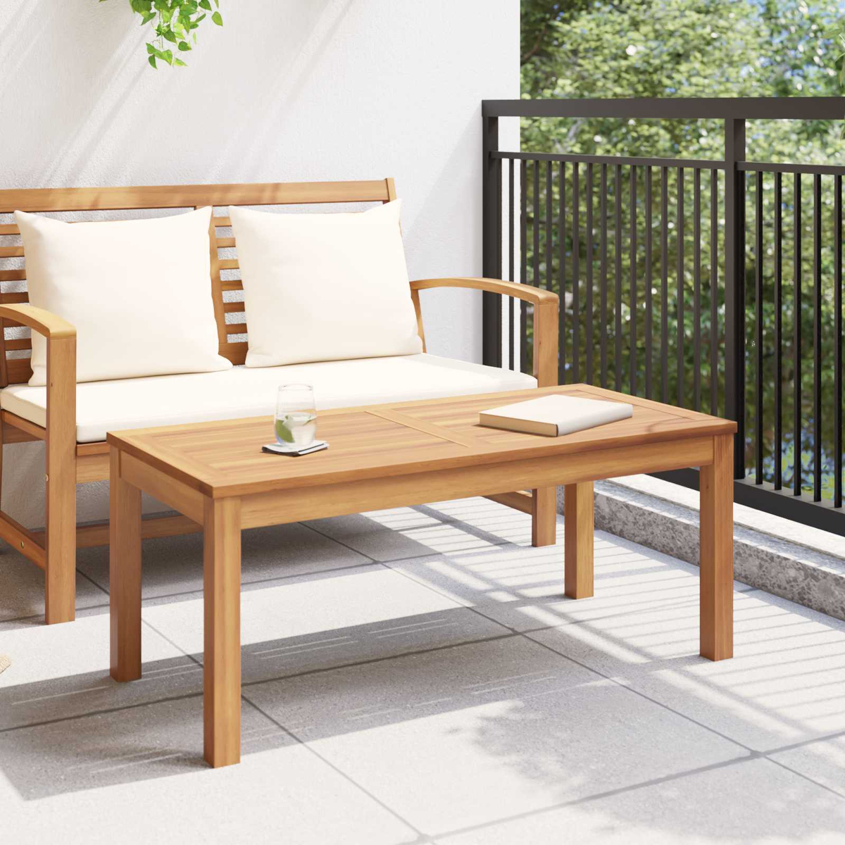 Un set da patio in legno con divano e tavolino. Ci sono cuscini, un bicchiere d'acqua e un libro sul tavolo.