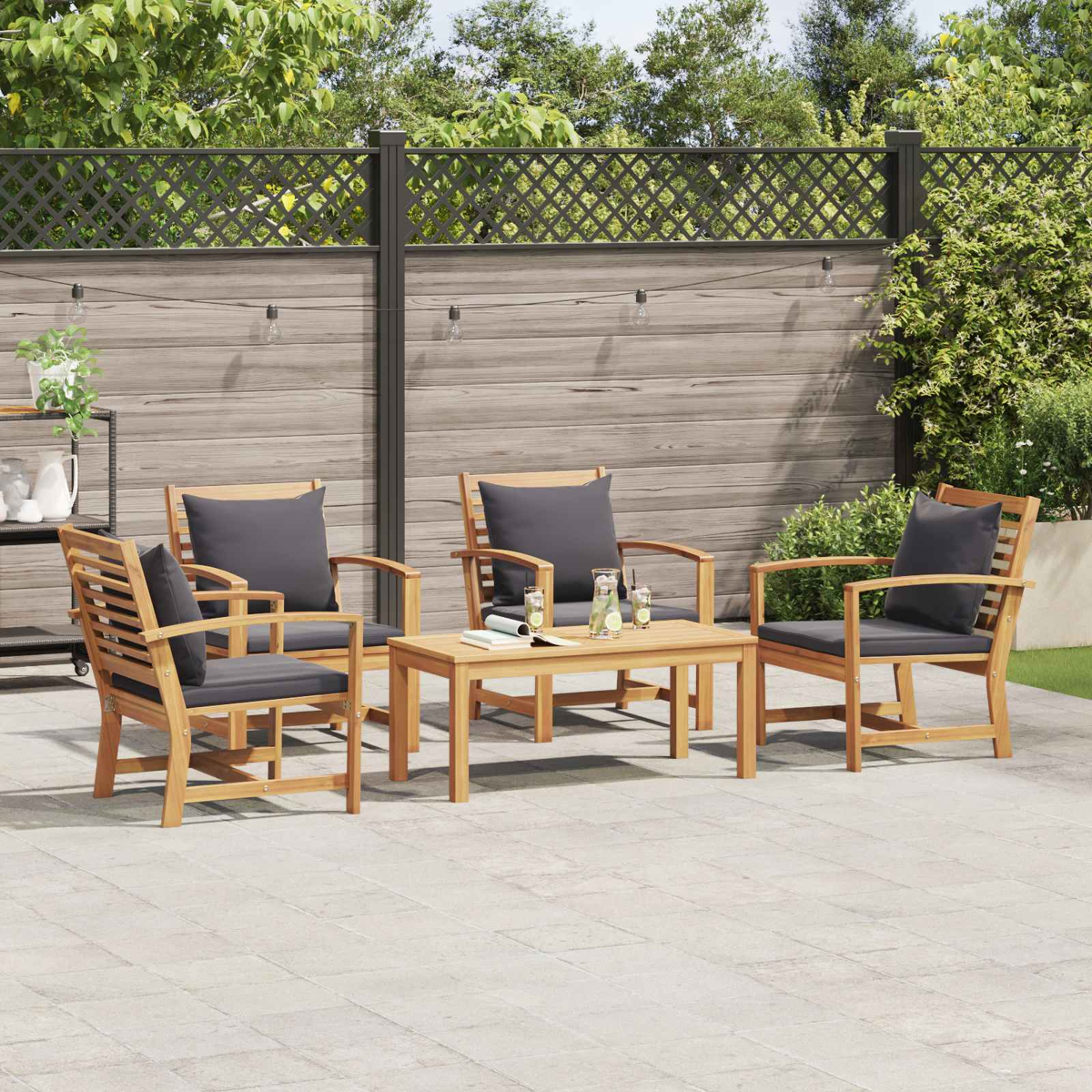 Garten-Terrassenset mit vier Holzstühlen, grauen Kissen und einem Tisch. Der Hintergrund umfasst einen Zaun, Pflanzen und Lichterketten.