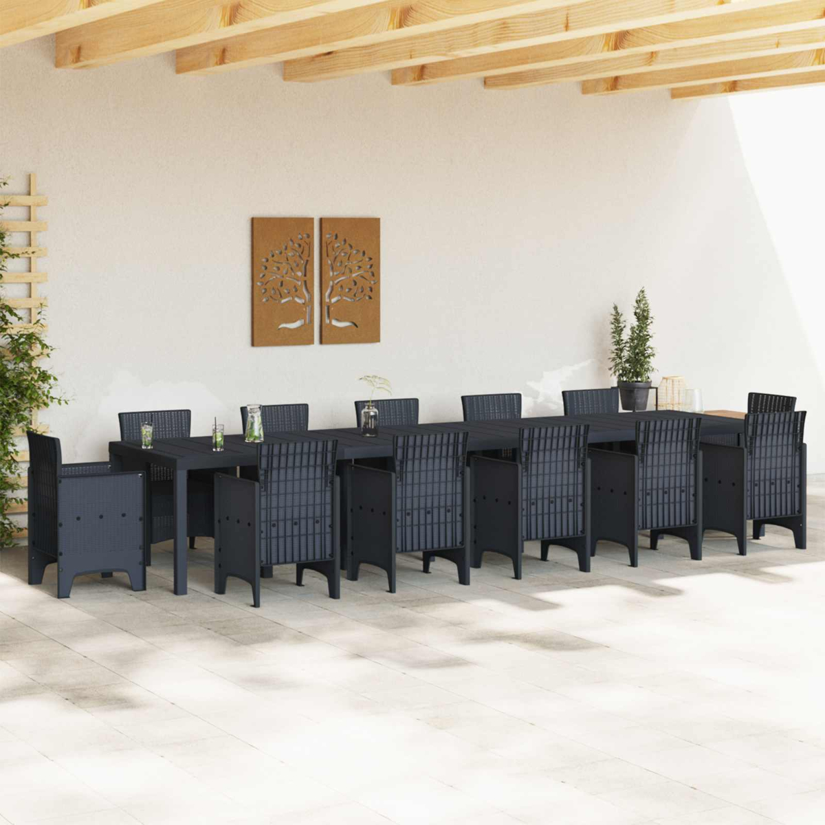 Essgruppe im Freien. Ein langer schwarzer Tisch mit Stühlen unter einem Holzdach. Zwei Wandkunstwerke und Pflanzen.