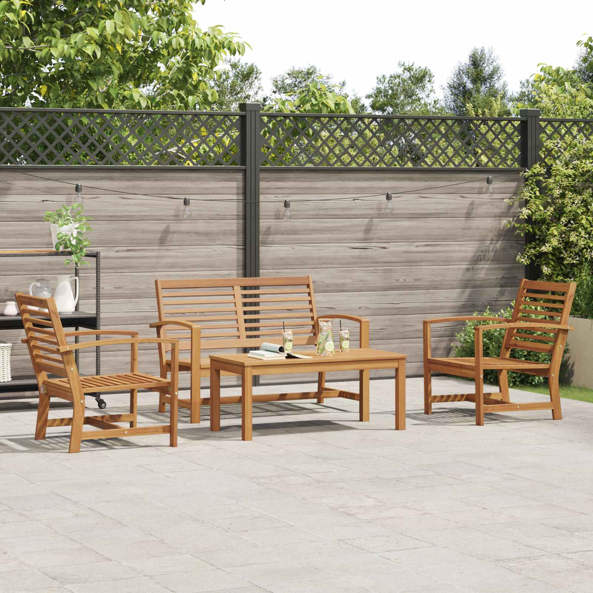 Gartenmöbel-Set aus Holz: Sofa, zwei Stühle und ein Tisch auf einer Terrasse. Zaun und Grün im Hintergrund.