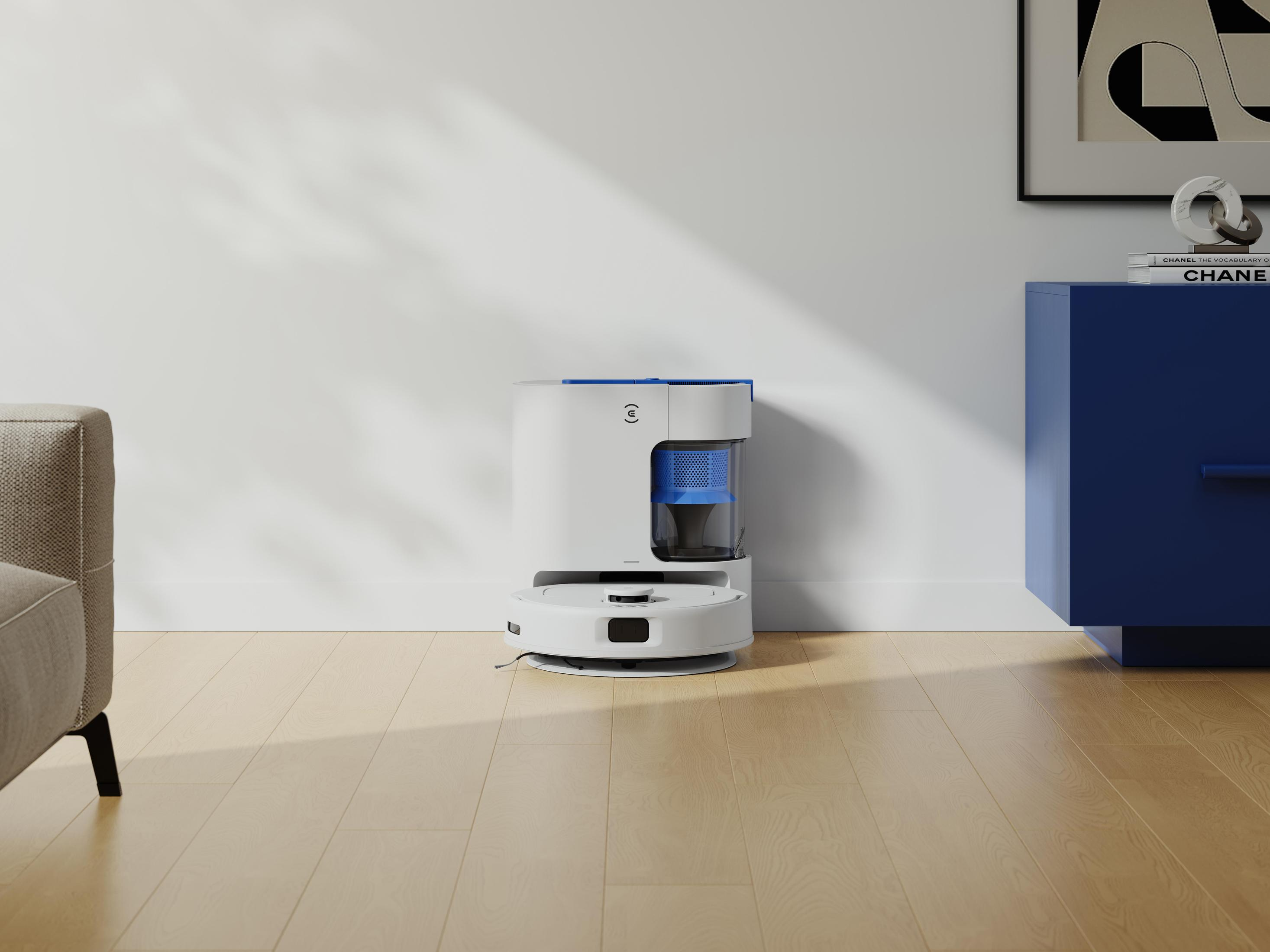Ein weiß-blauer Roboter-Staubsauger auf einem Holzboden, in der Nähe eines blauen Schranks und eines beigen Sofas.