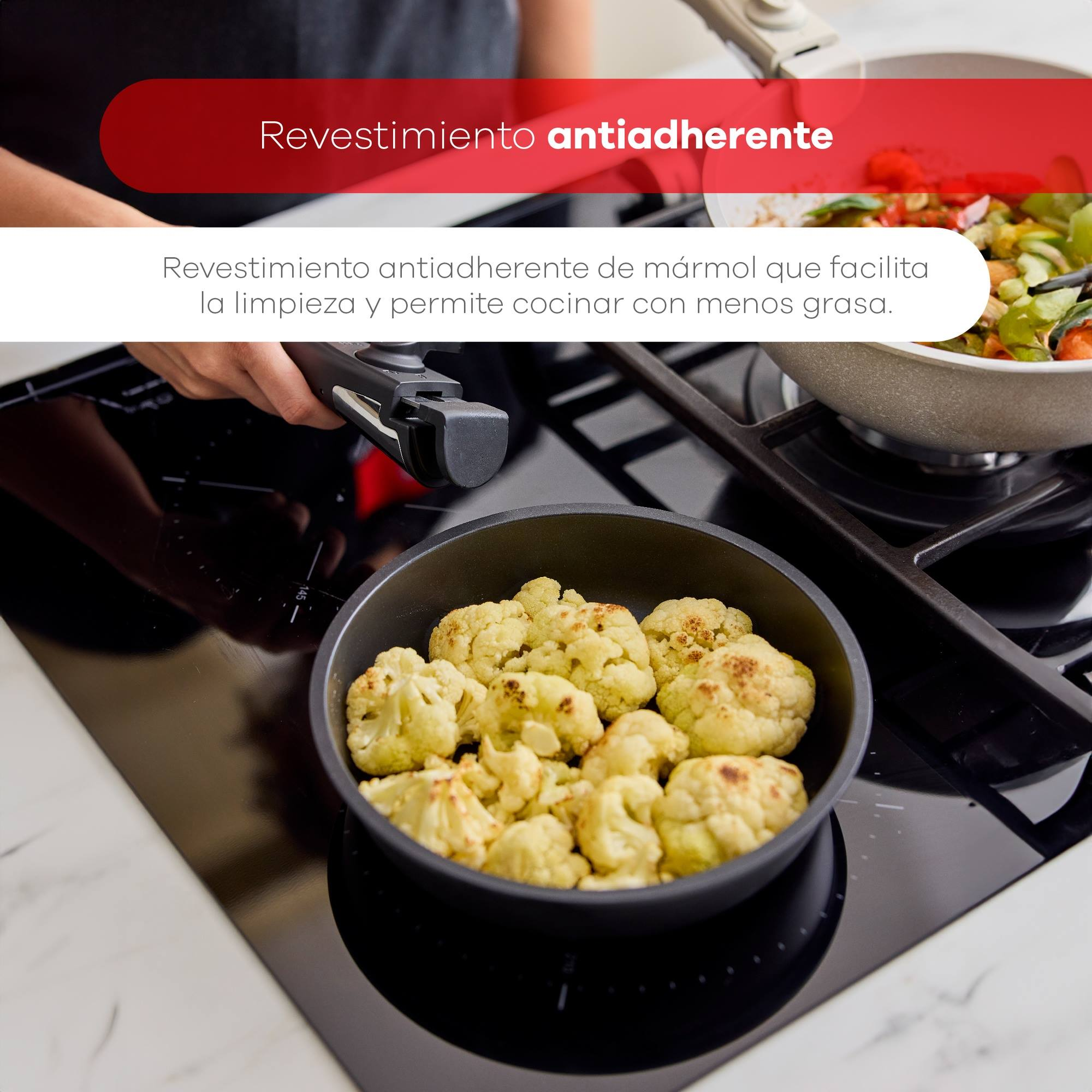 Ramilletes de coliflor cocinándose en una sartén sobre una estufa negra. Otra sartén con ensalada a la derecha.