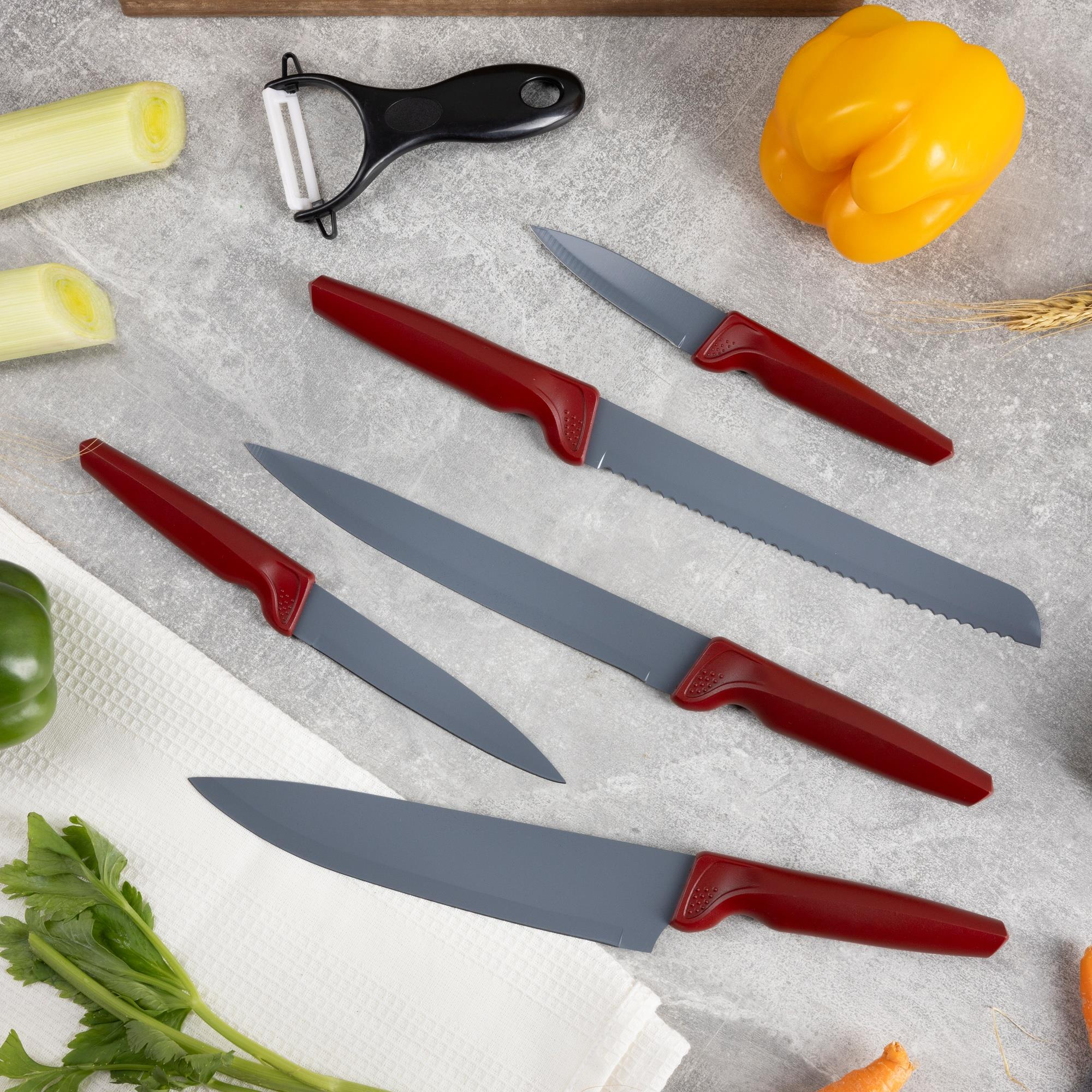 La imagen muestra cuchillos de cocina, verduras y un pelador sobre una superficie gris. Los cuchillos son rojos y grises. Las verduras son verdes y amarillas.