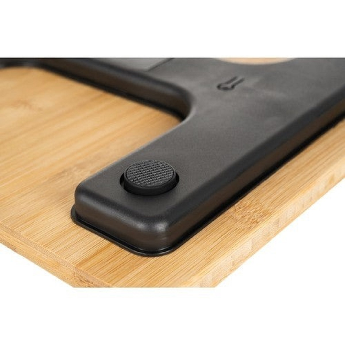 Primer plano de una tabla de cortar de bambú con un mango negro. El mango tiene un botón redondo y texturizado.