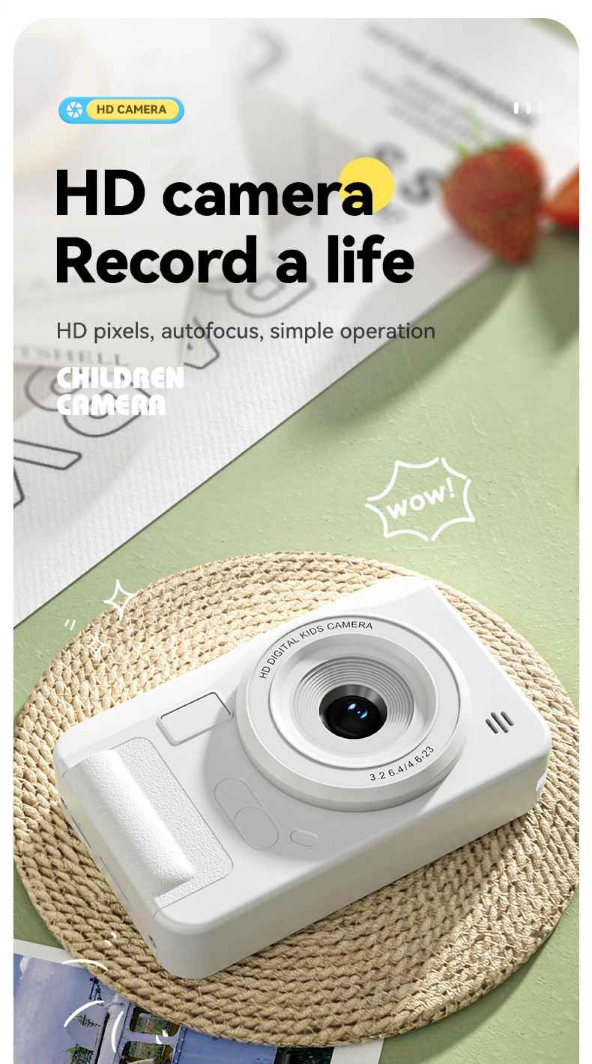 Eine weiße Kinderkamera auf einer gewebten Matte, mit dem Text 'HD-Kamera Record a life'. Im Hintergrund ist eine Erdbeere zu sehen.