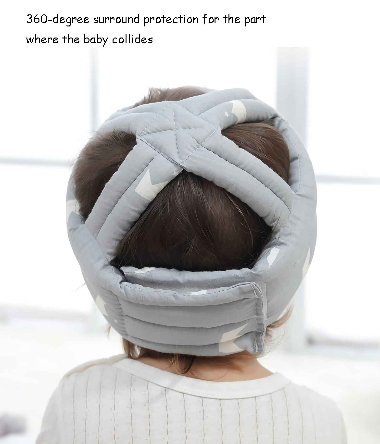Ein Baby trägt einen grauen Kopfschutz. Es hat weiße Sterne. Das Baby trägt ein weißes Hemd.