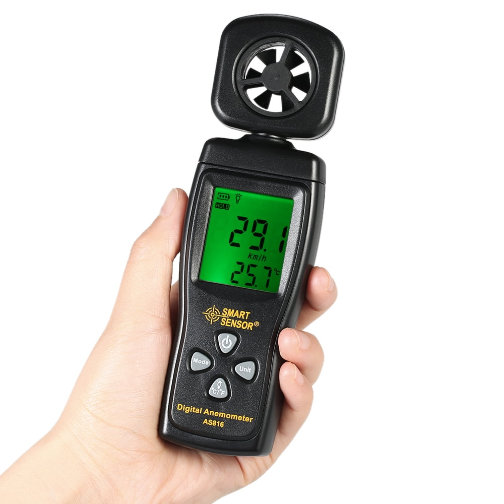 Eine Hand hält ein schwarzes digitales Anemometer. Der Bildschirm zeigt Messwerte an. Das Gerät hat einen fächerartigen Sensor oben.