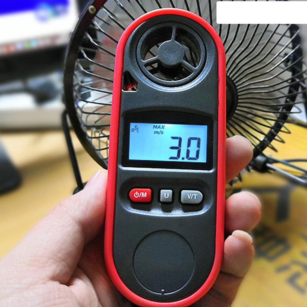 Eine Hand hält ein Windgeschwindigkeitsmessgerät mit 3,0 m/s. Es ist schwarz und rot, mit einem kleinen Ventilator dahinter.